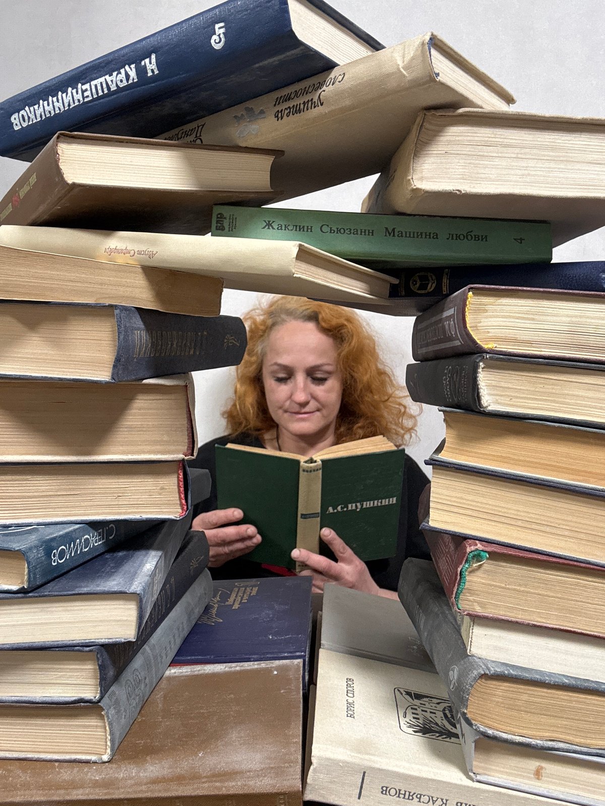 Reader surrounded by towering book stacks in Chaikovsky