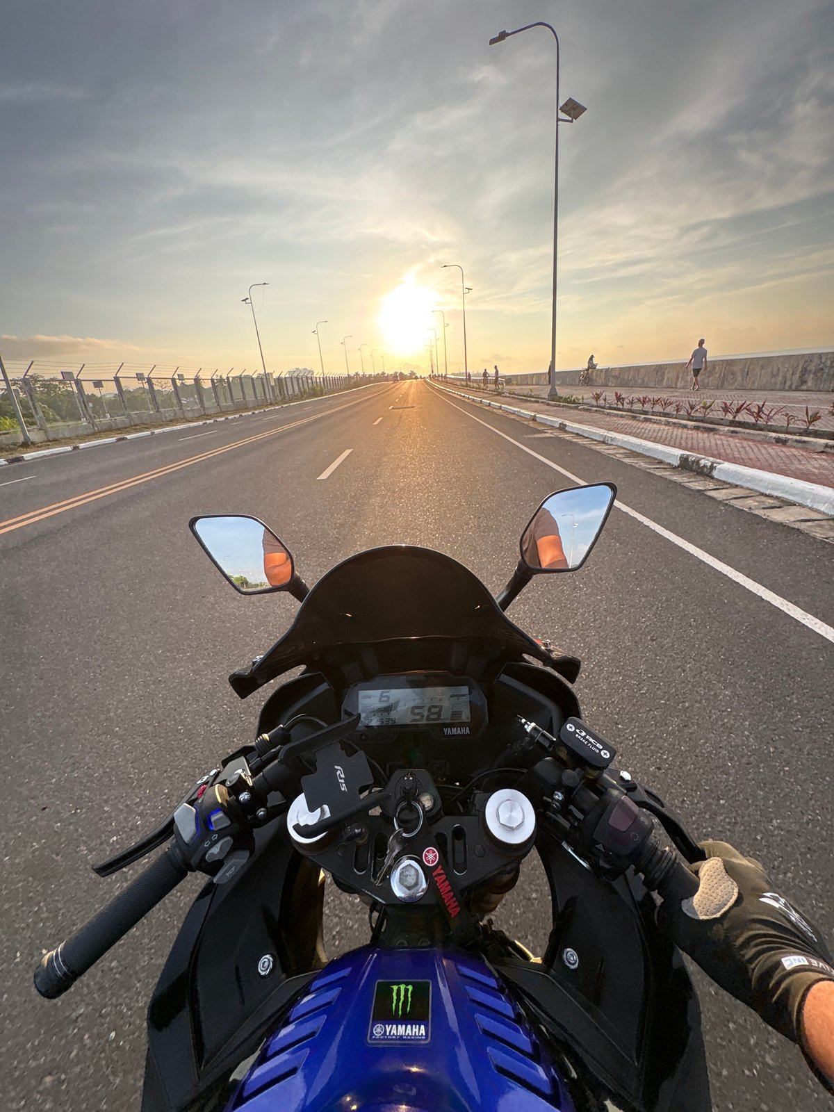 Motorcyclist rides Yamaha on Davao City highway at sunset