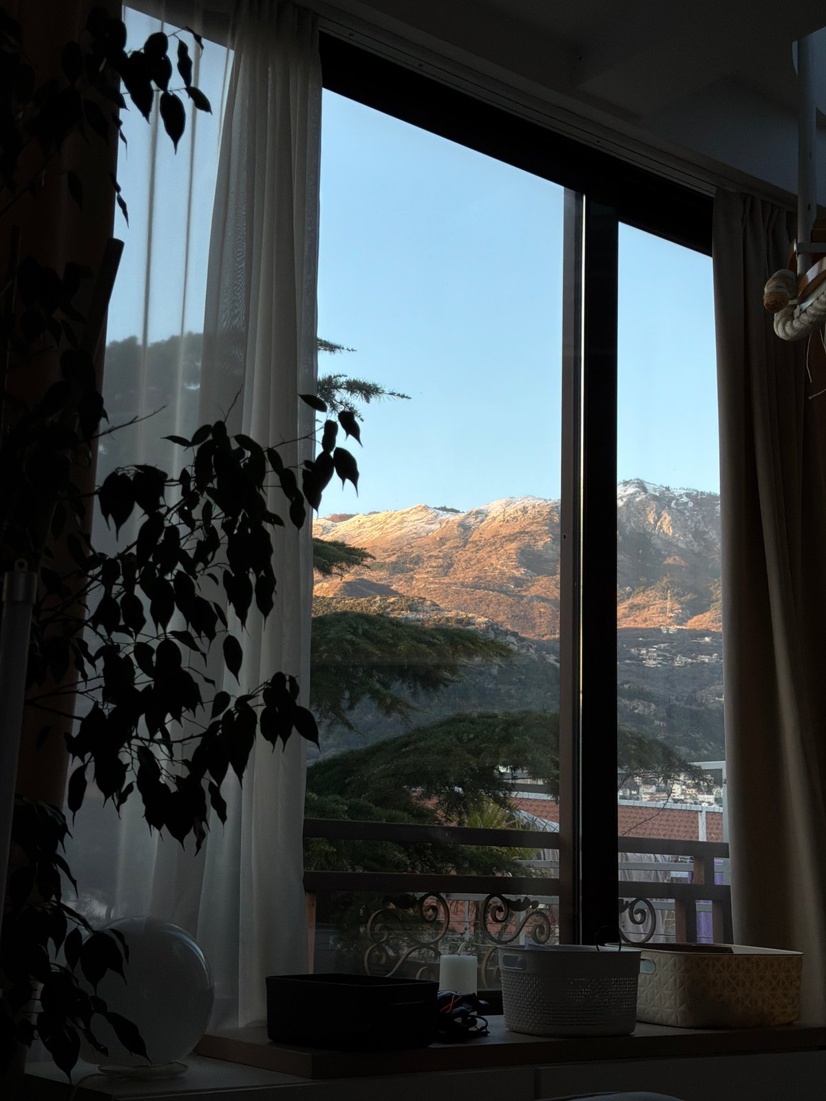 Indoor window view captures Montenegro mountain landscape in Budva