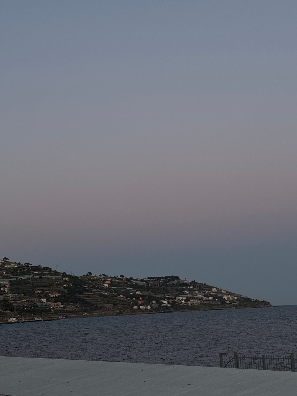 Dog walker strolls waterfront path in Sanremo evening