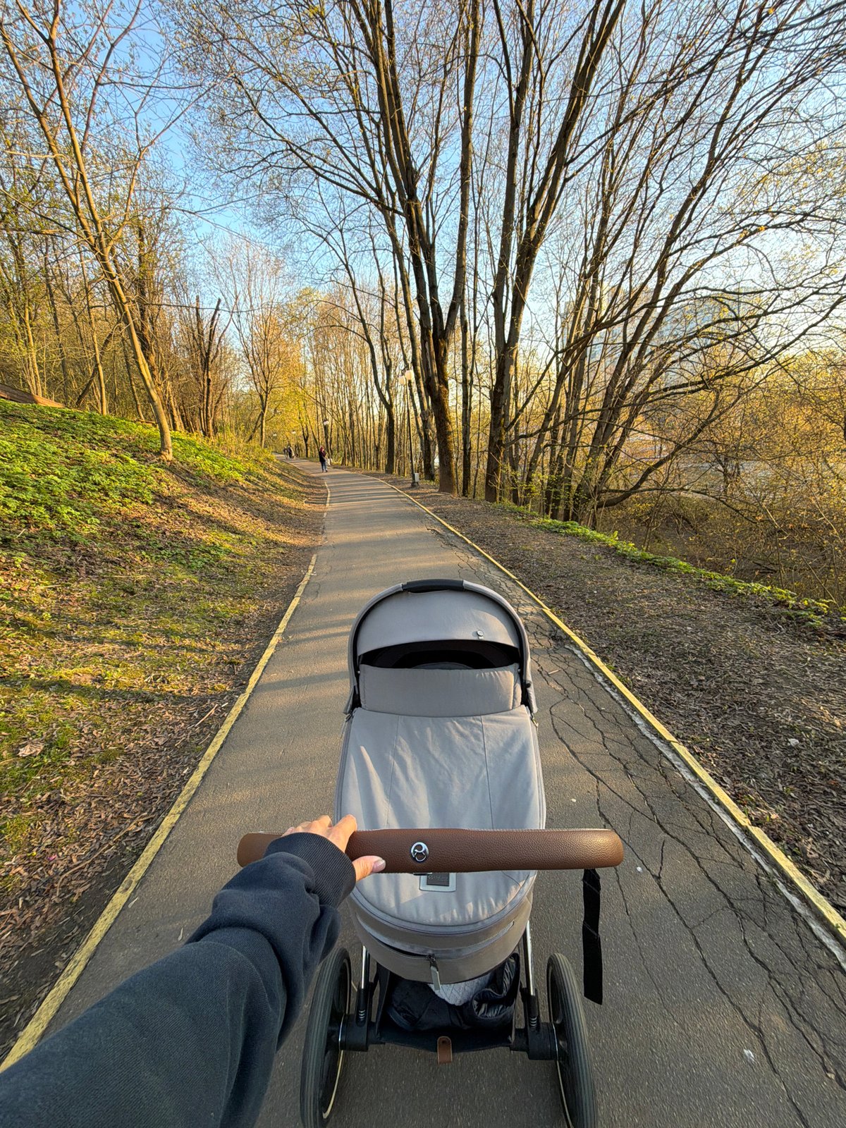 Woman with stroller enjoys afternoon park walk in Khimki