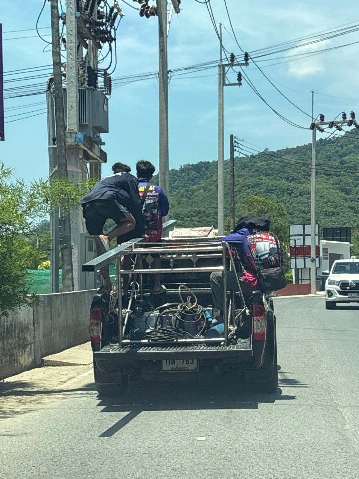 Pickup truck carries three passengers through Choeng Thale vegetation