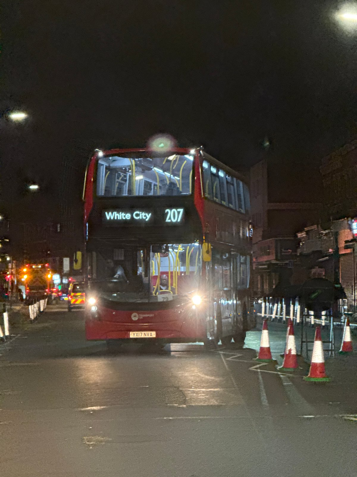London double-decker bus travels wet streets at night