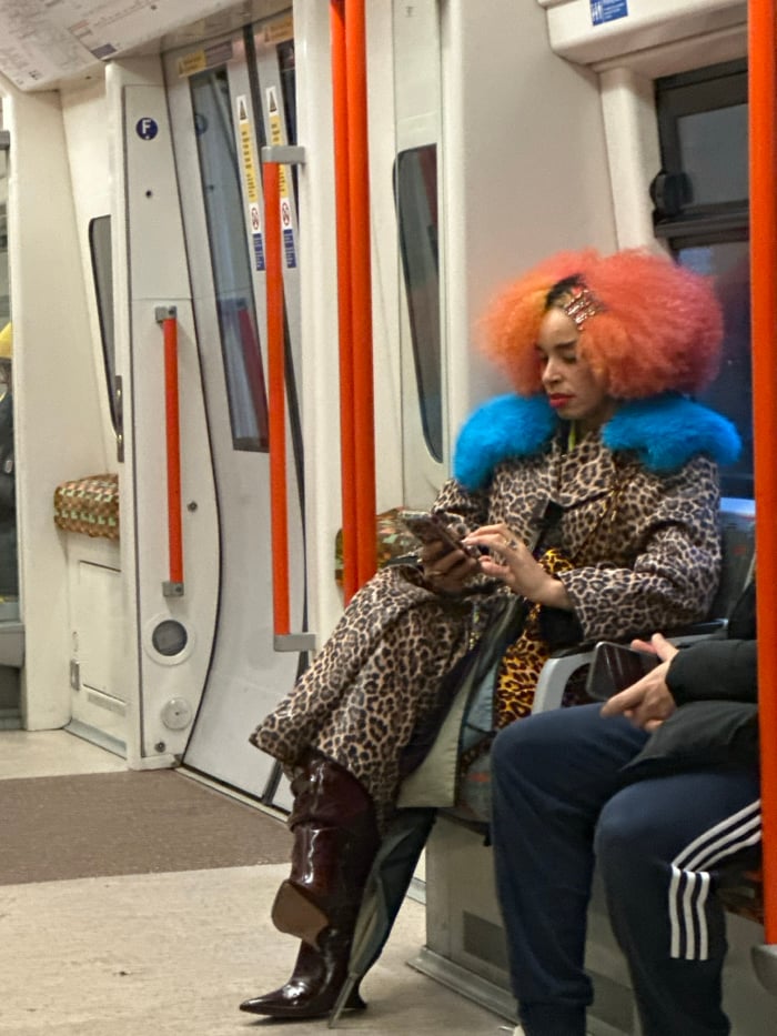Colorfully dressed passenger rests on London train