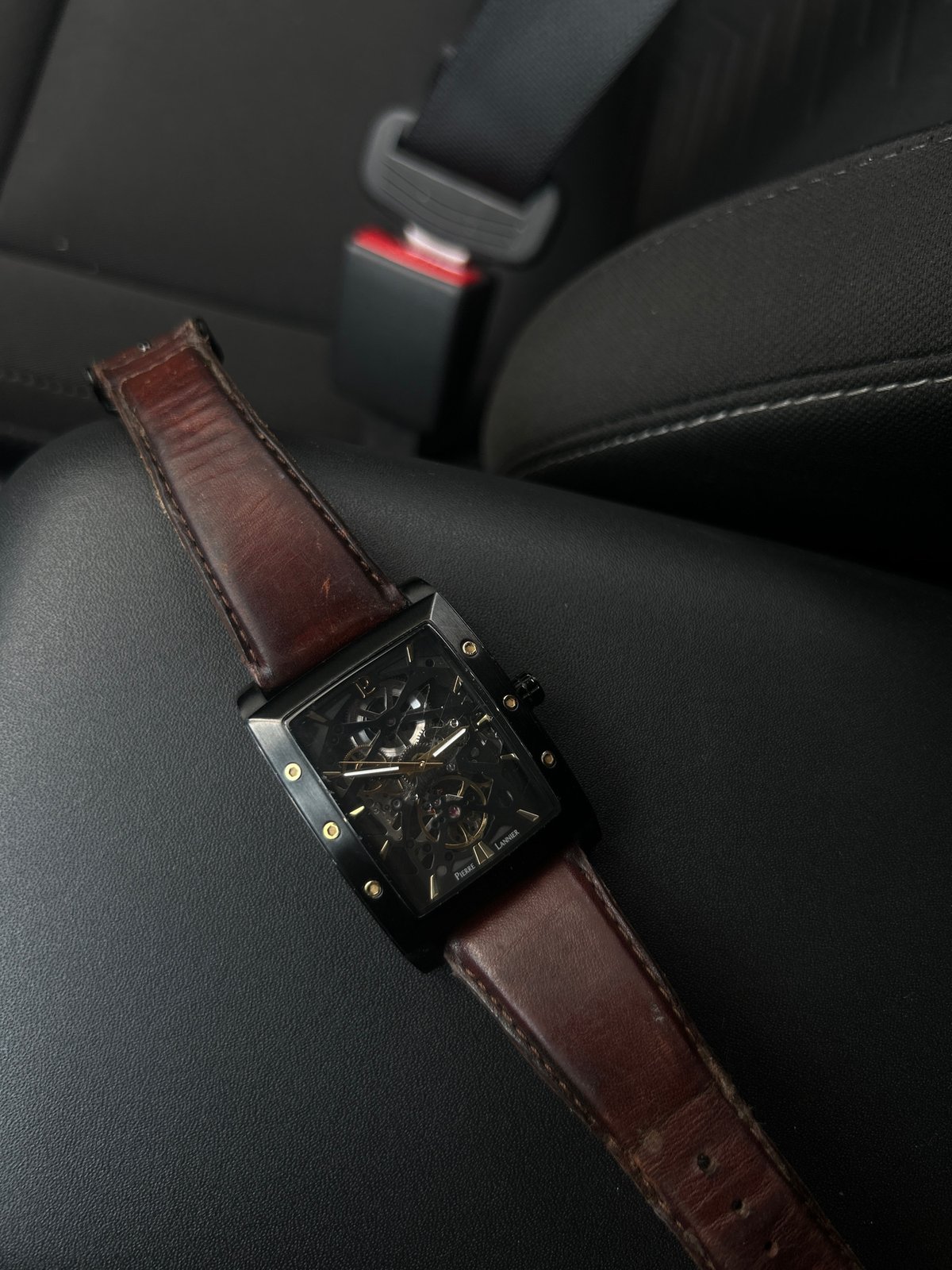 Person examines skeleton watch inside parked vehicle during midday