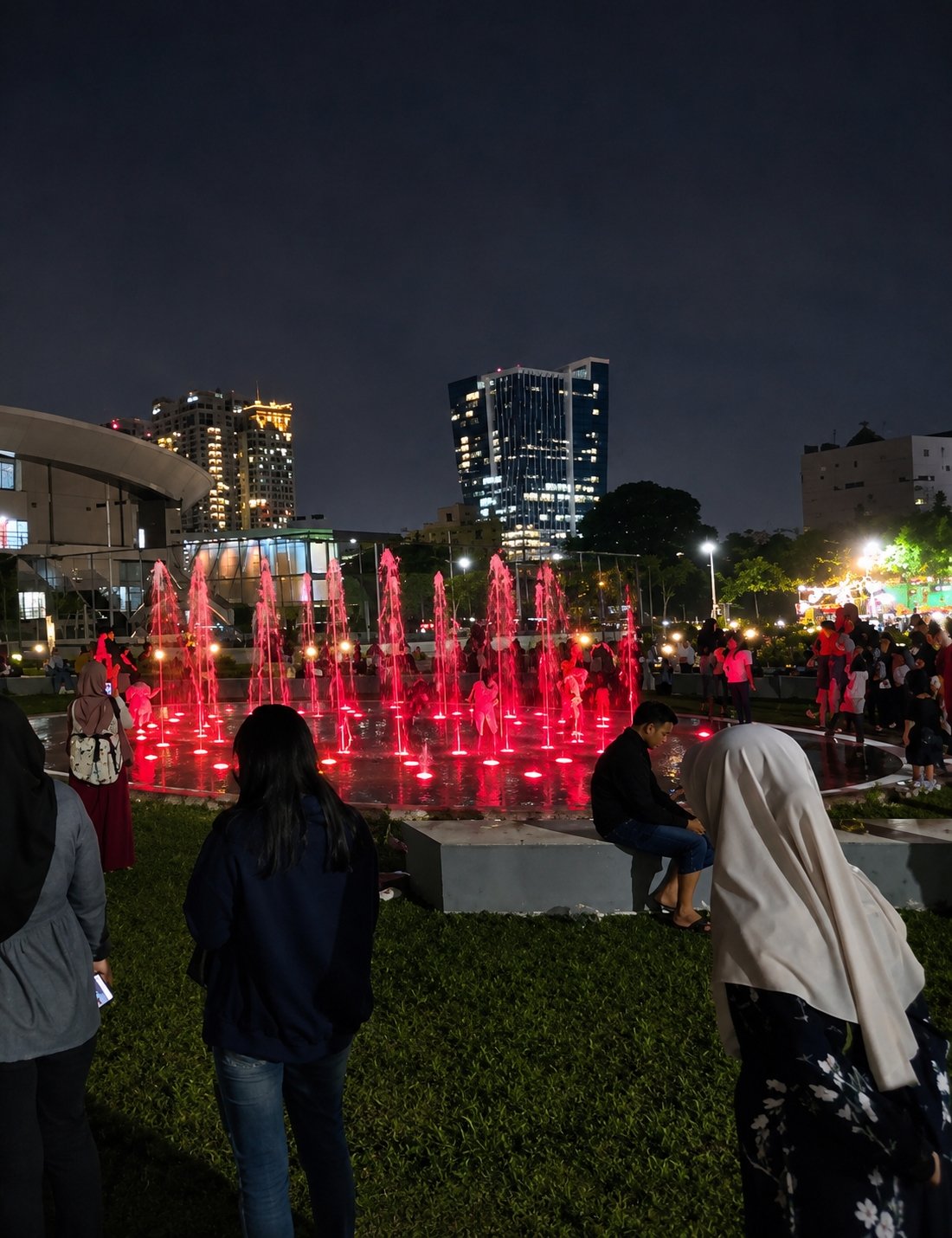 Evening crowd gathers around lit fountain at Medan's Taman Kebun Bunga