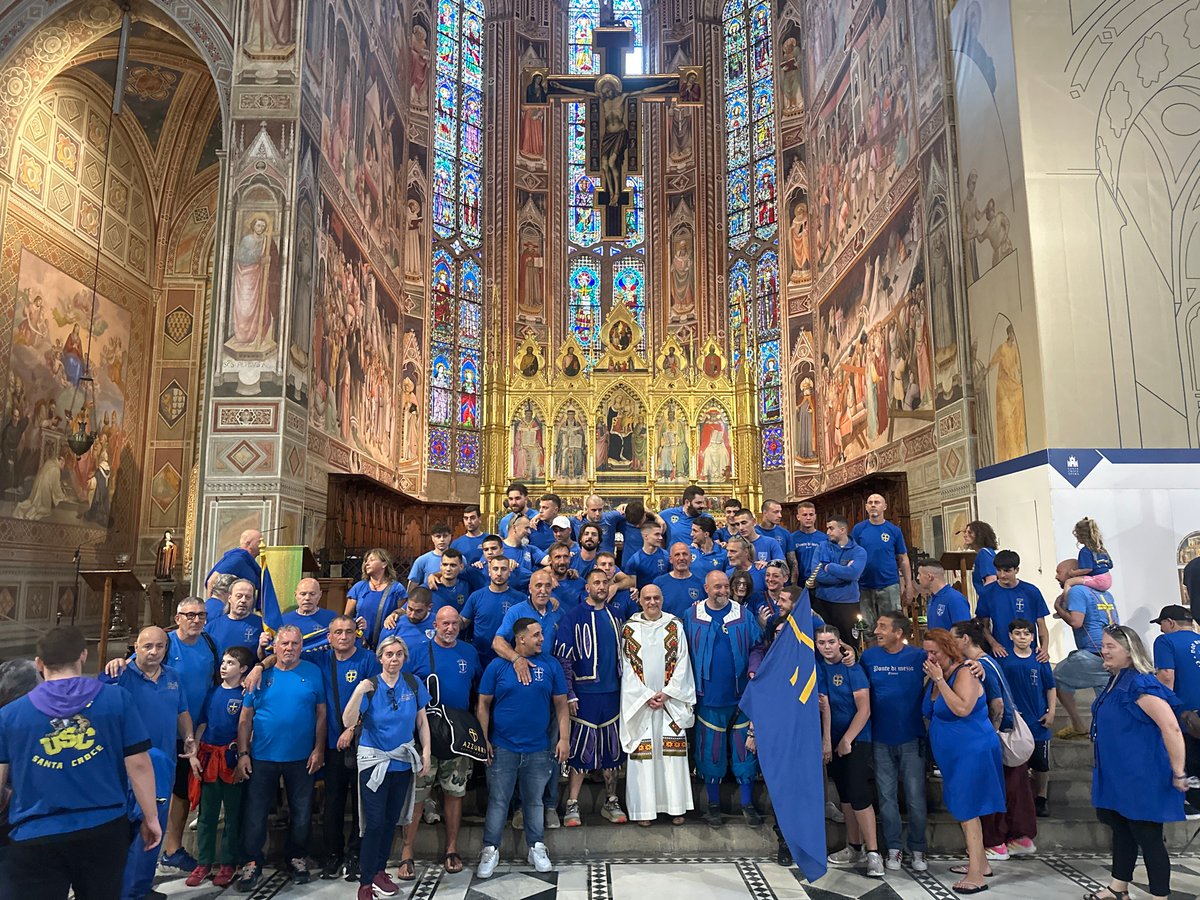 Blue-shirted group poses with cross flag inside Florence basilica