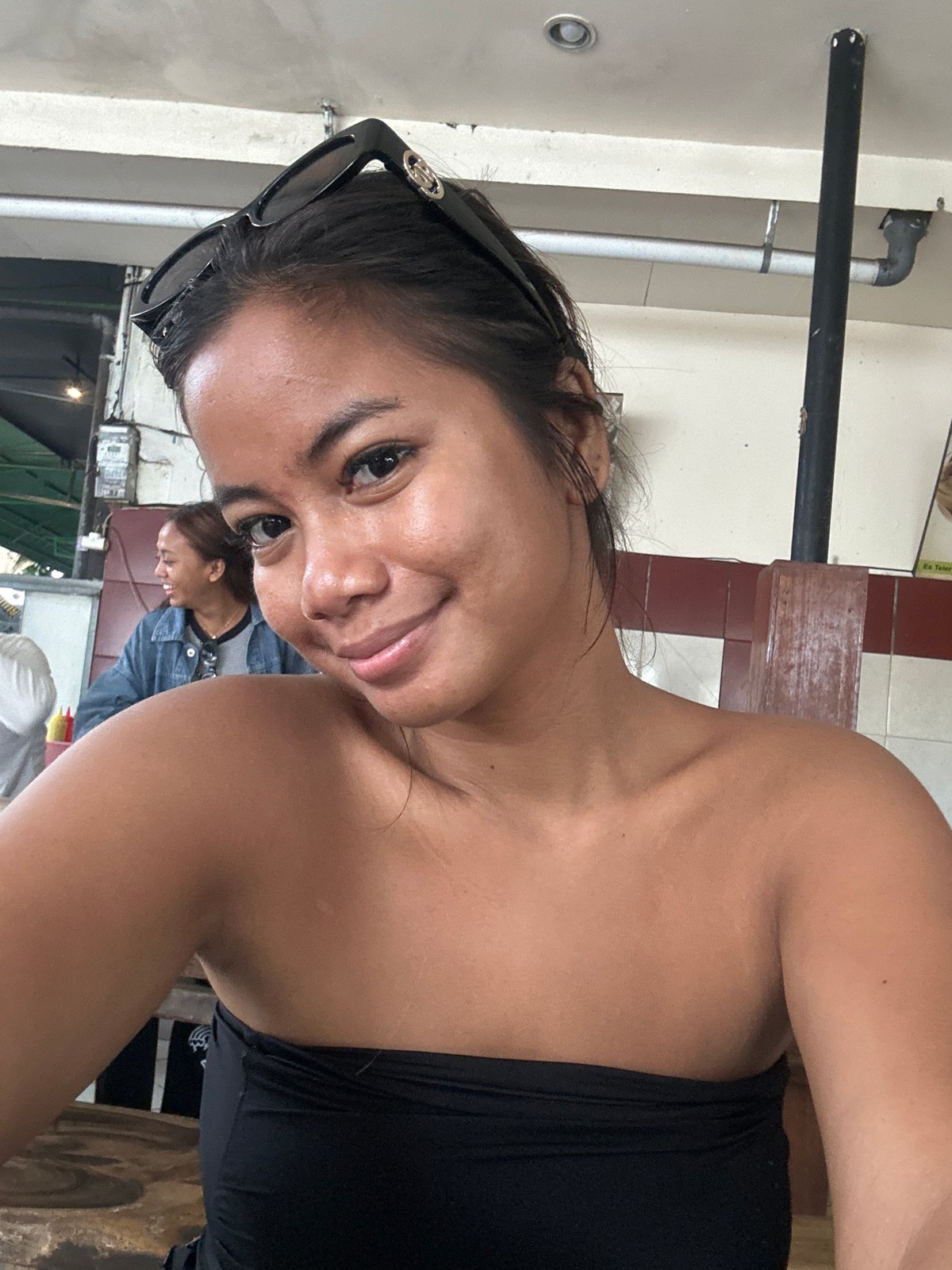 Woman Takes Selfies at Kuta Restaurant Amid Traditional Offerings