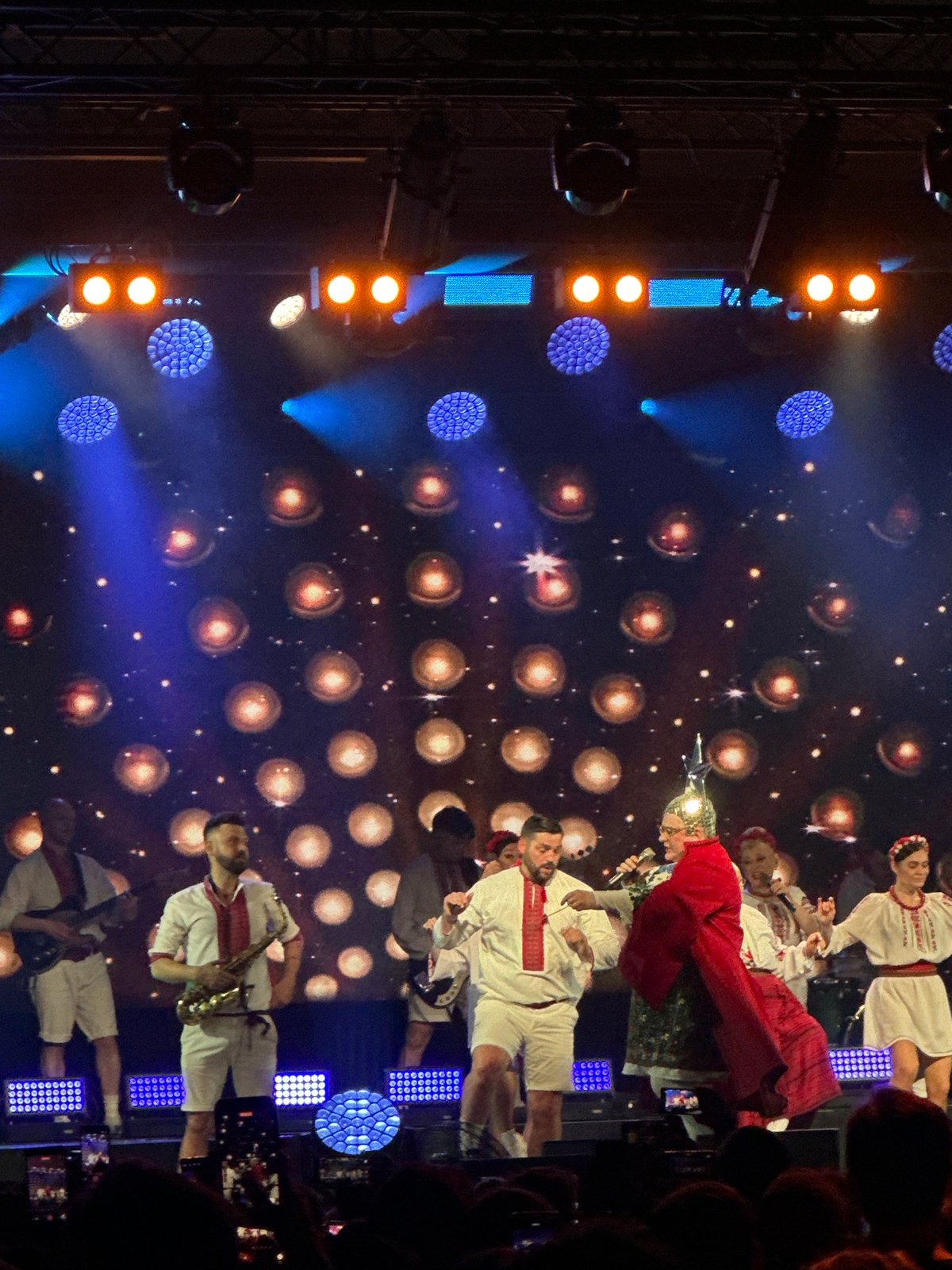 Music group performs at packed concert venue with elaborate lighting