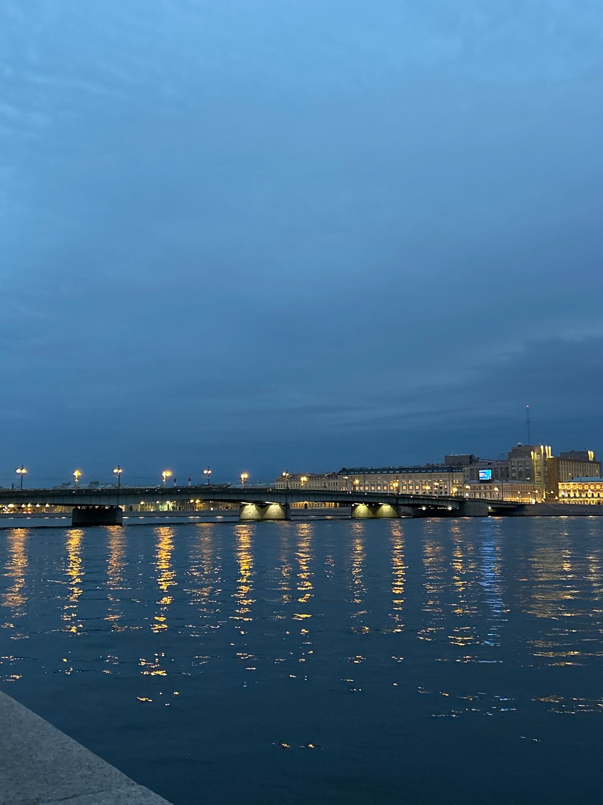 City river and bridge at dusk, lights reflected on water