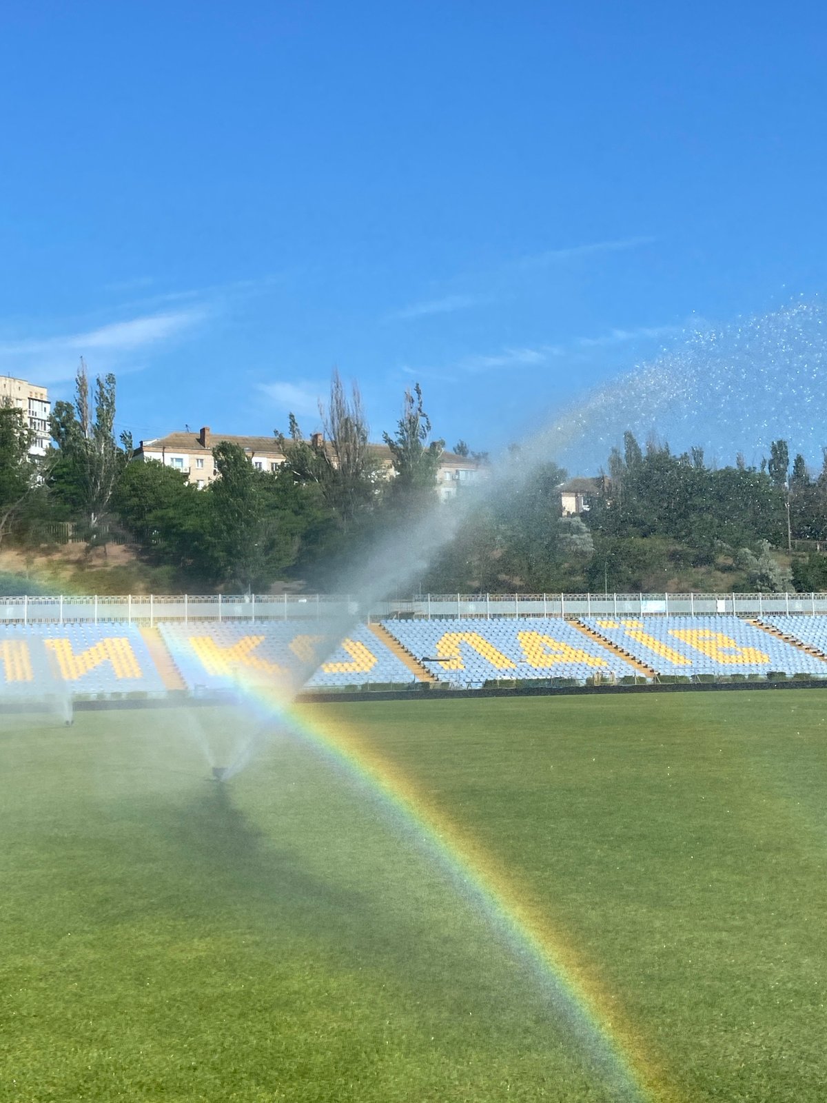 Jump roping on the track while sprinklers rainbow the field