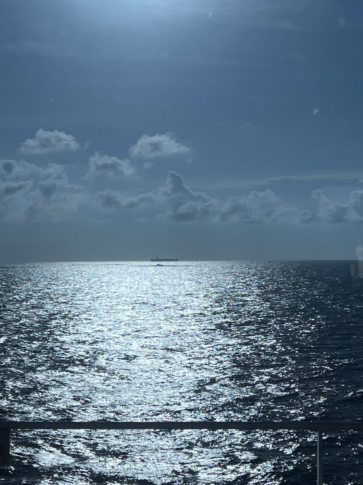 Sunlight reflects across open ocean under a midday sky