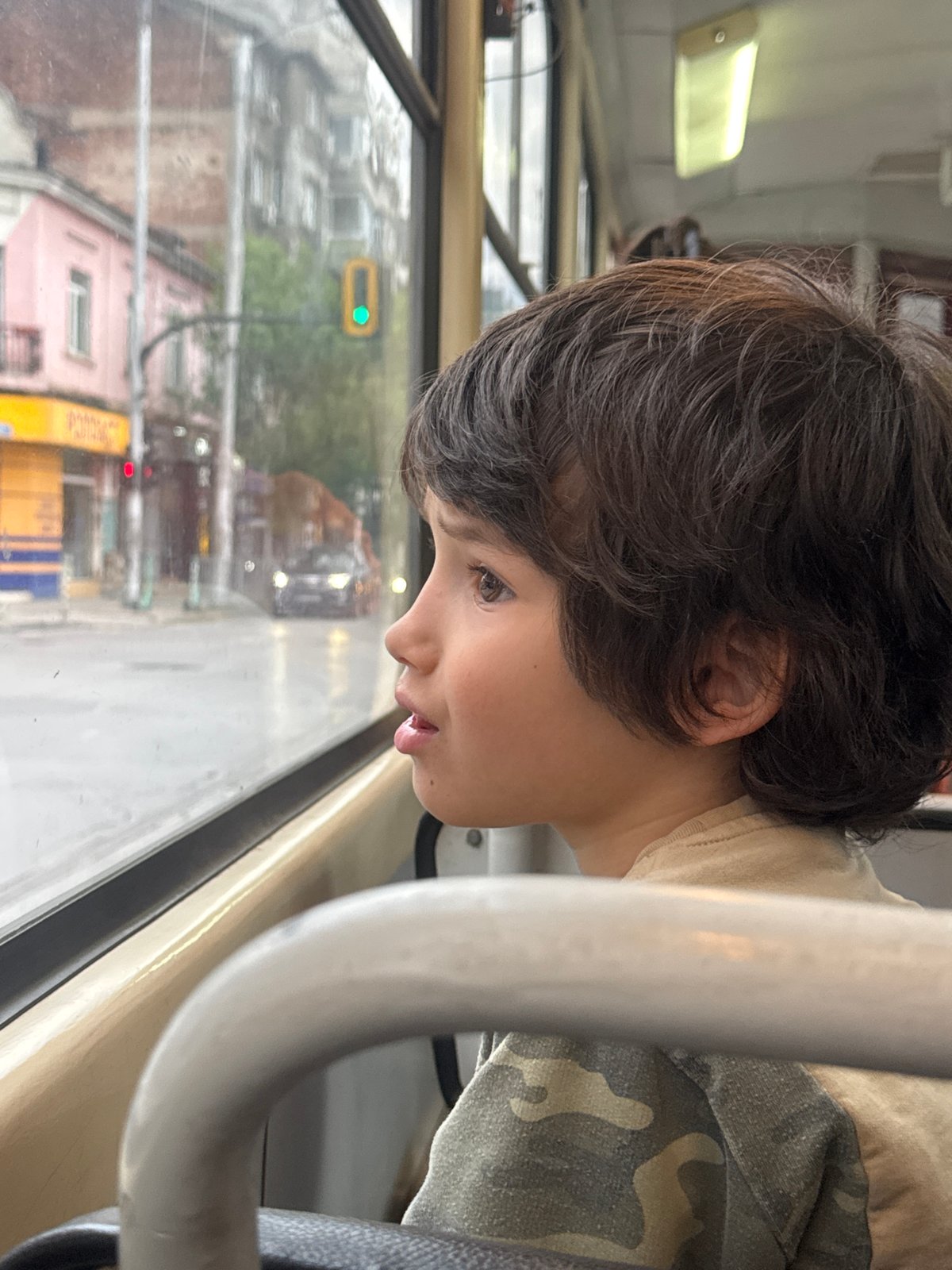 Boy gazes from bus window in Sofia street scene