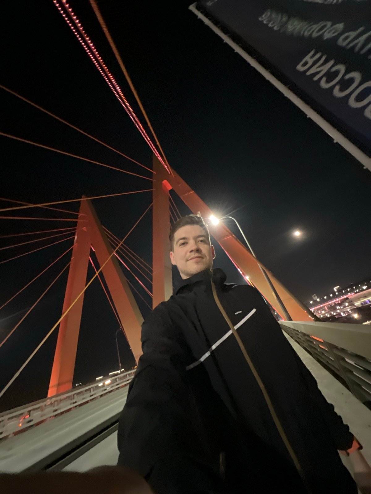 Man films nighttime selfies on illuminated Millennium Bridge in Kazan