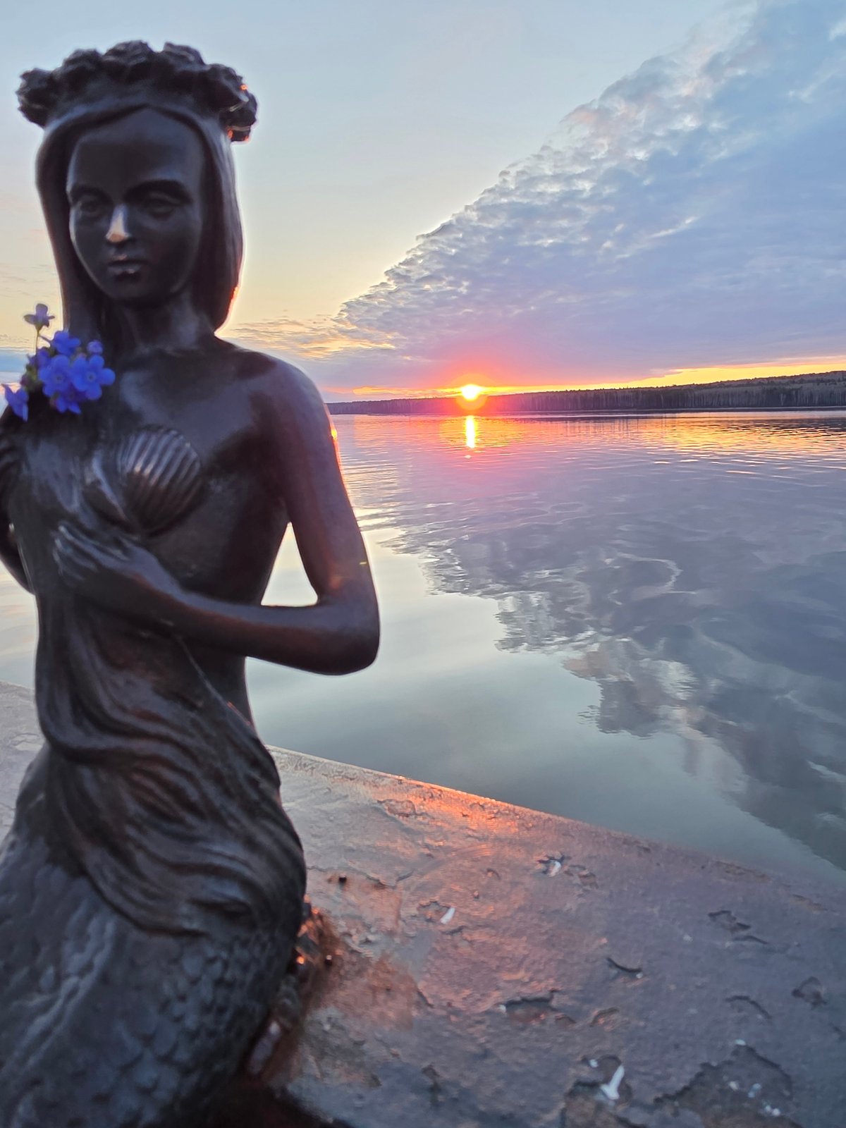 Sunset celebration documented at Chaikovsky waterfront with flowers, statue