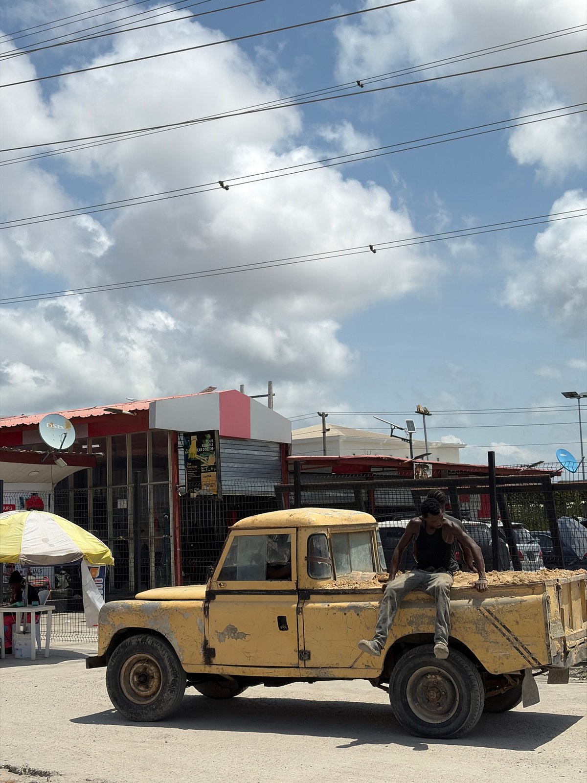 Man boards yellow truck outside store in Igboefon, Nigeria