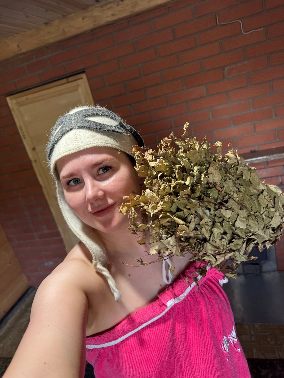 Woman spotted in traditional sauna attire with birch broom