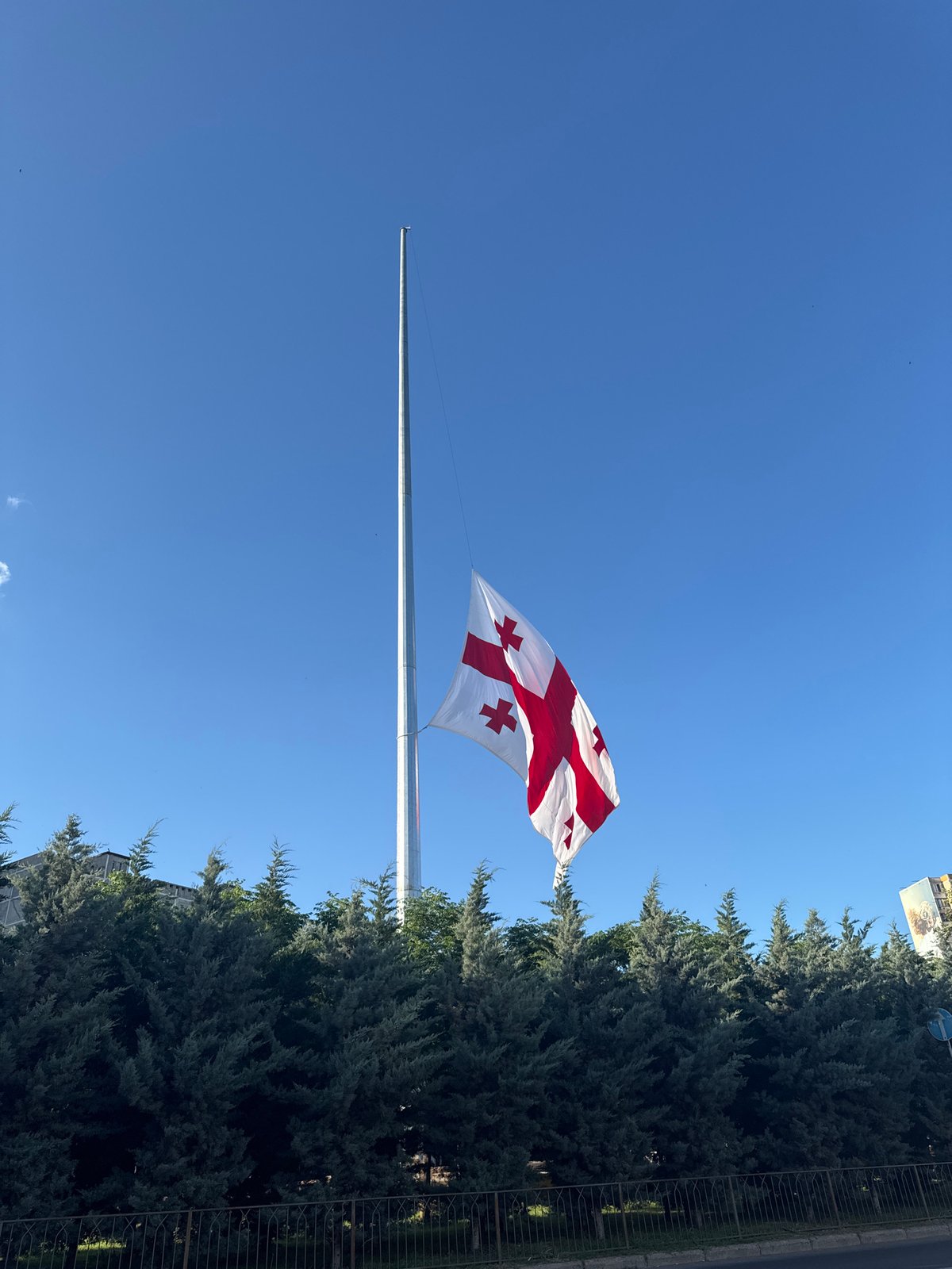 Georgian flags at half-mast near a mural-covered Tbilisi apartment block