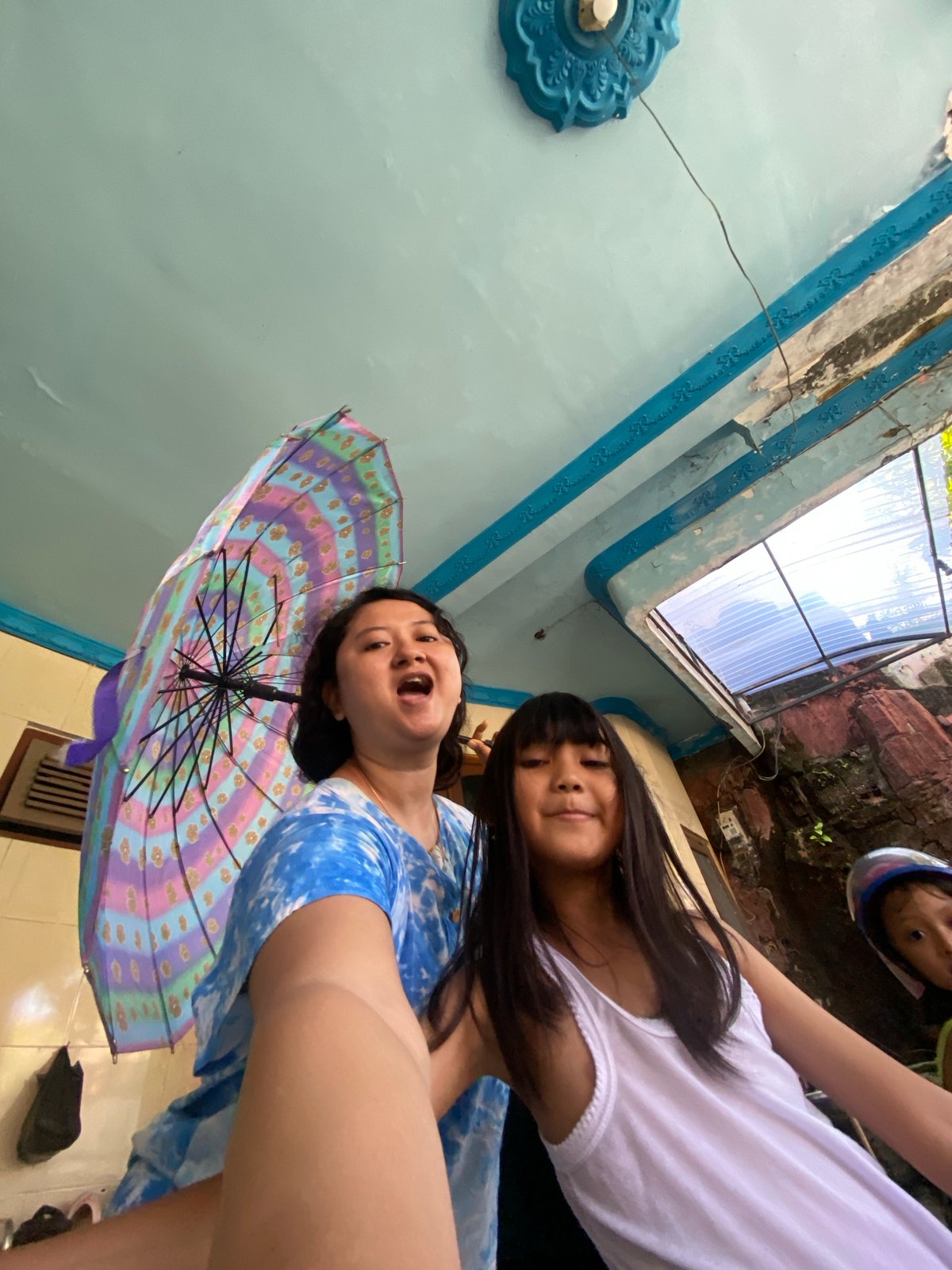 Family plays with brooms, umbrellas, bikes in Indonesia home