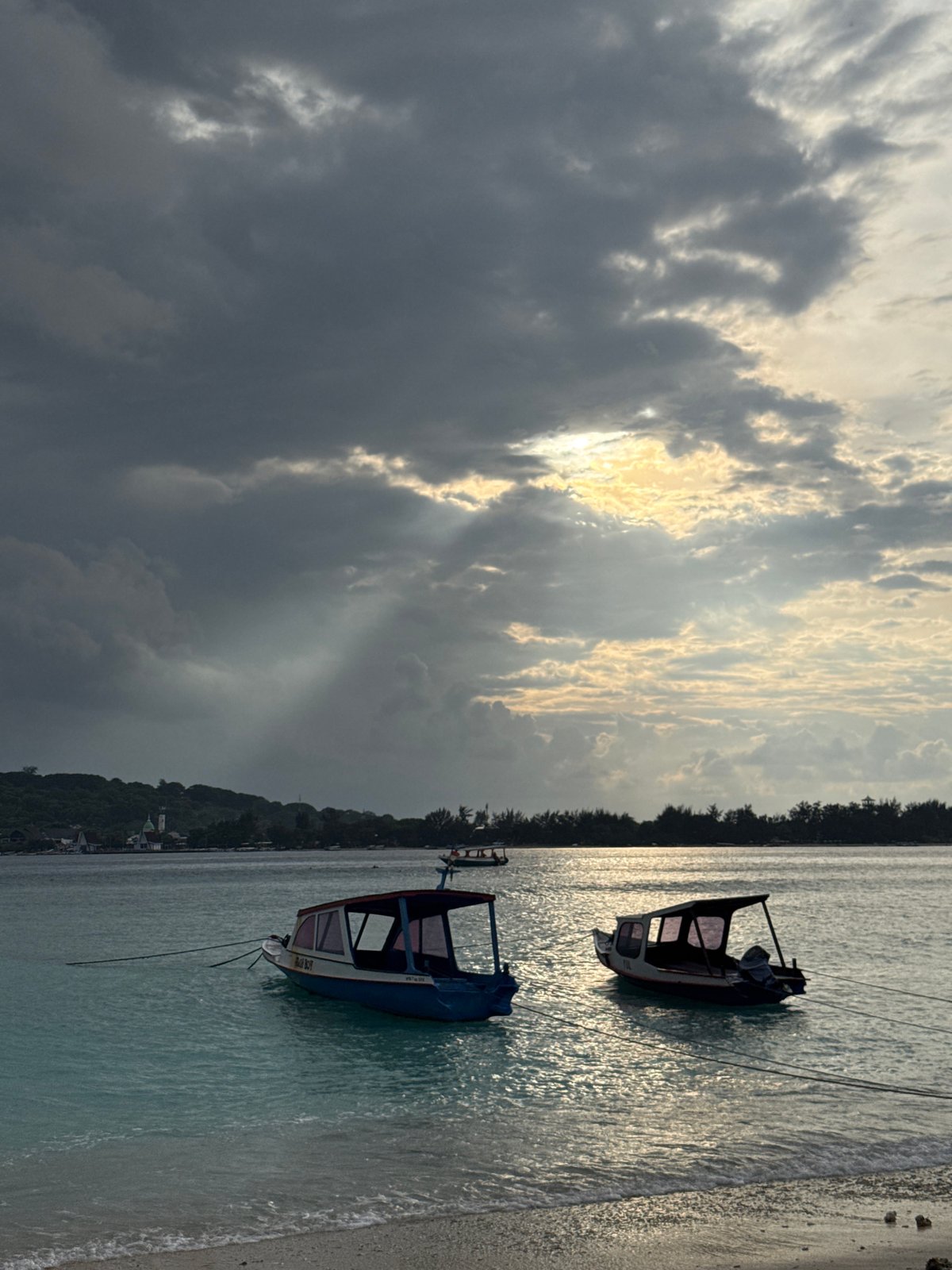 Two boats beached on Indonesian shore under cloudy skies