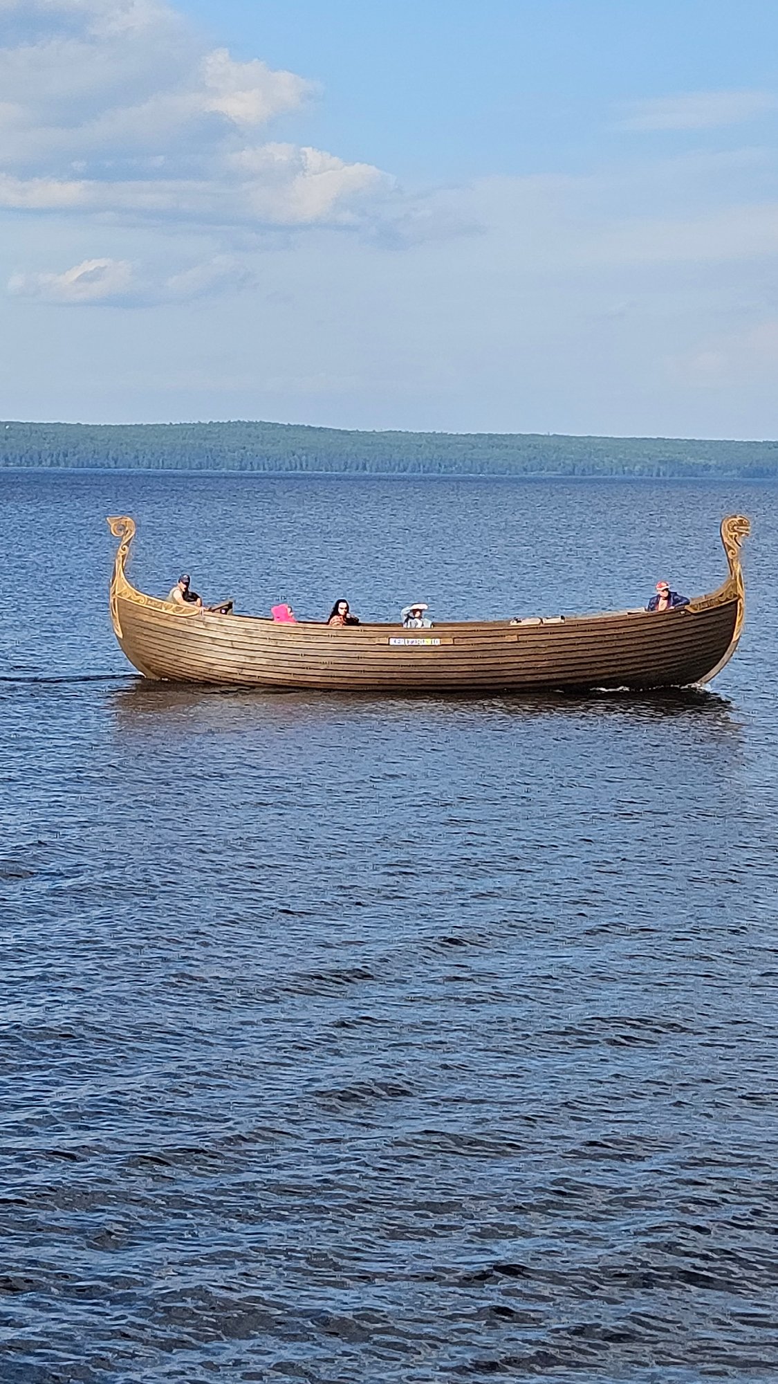 Sunny day at a waterfront park with Viking boats and kvas