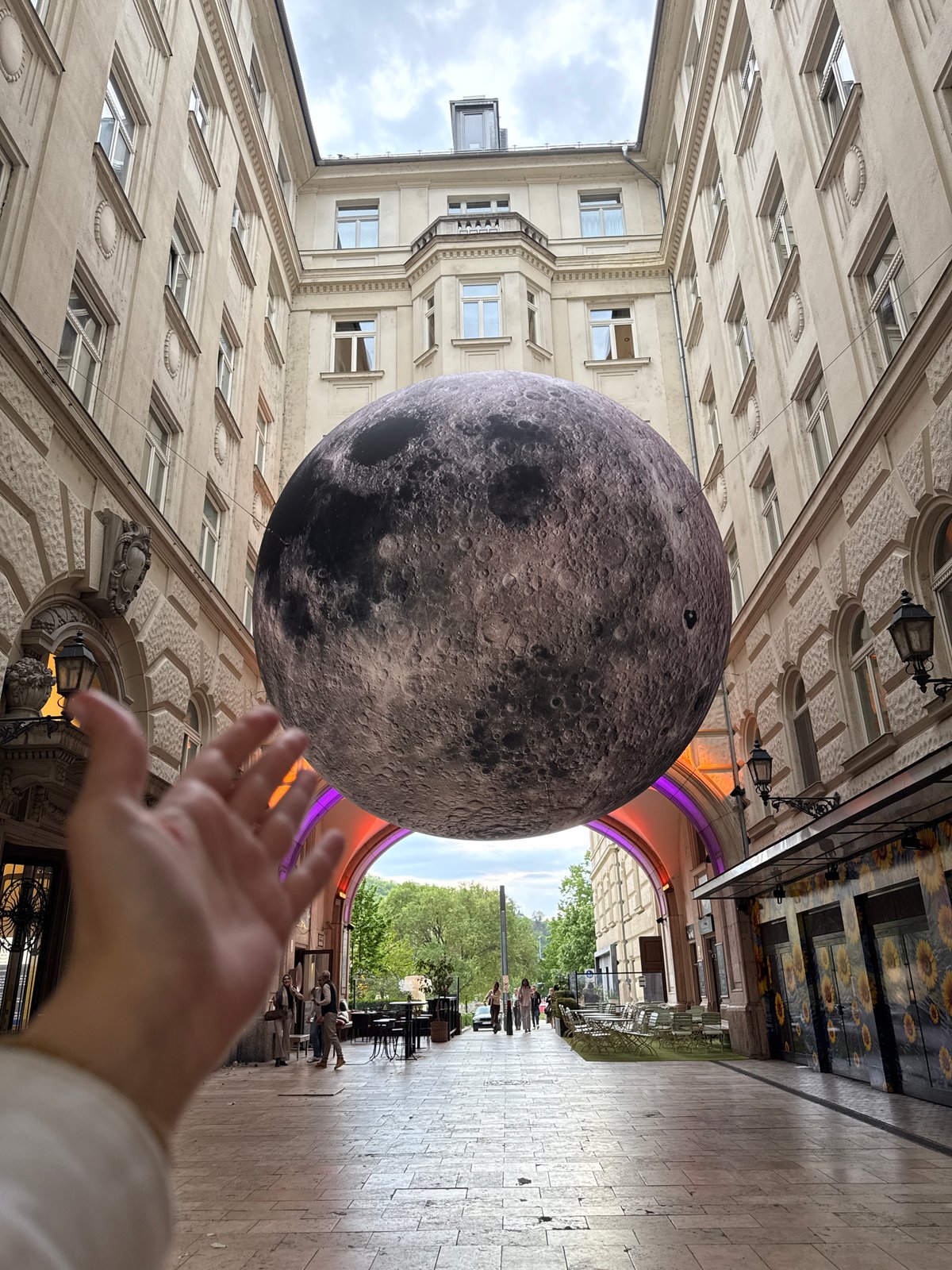 Moon art installation suspended between historic Budapest buildings