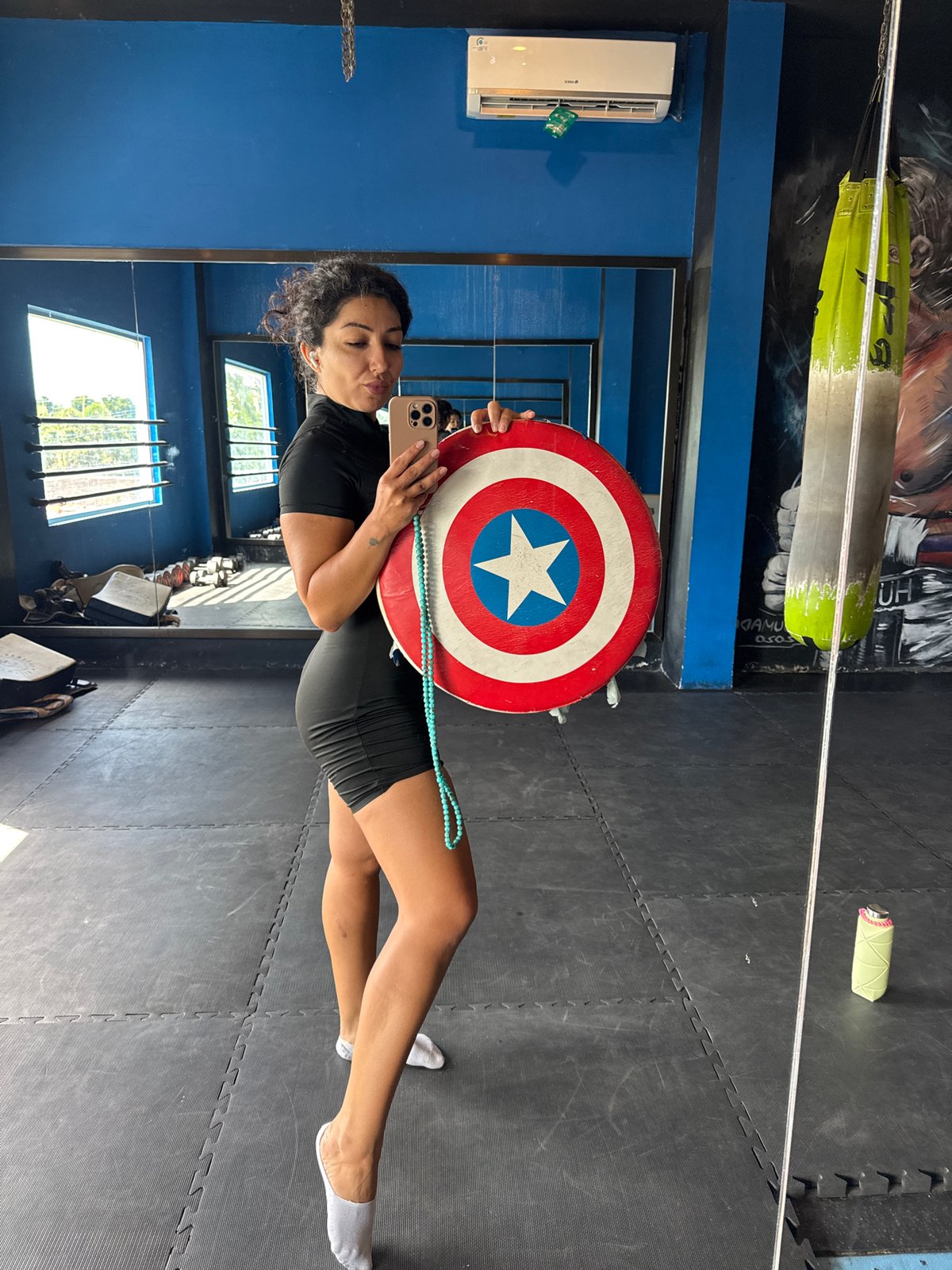 Woman poses with Captain America shield at Indonesian gym