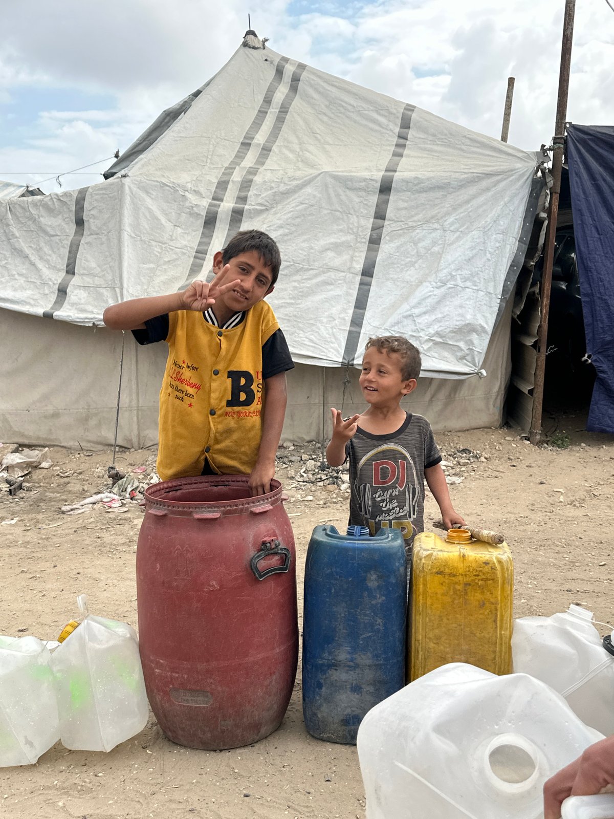 Children gather near water containers in Gaza refugee camp