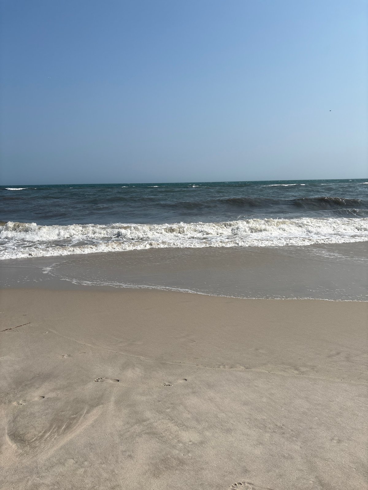 Barefoot beach walk, waves rolling in on a clear day