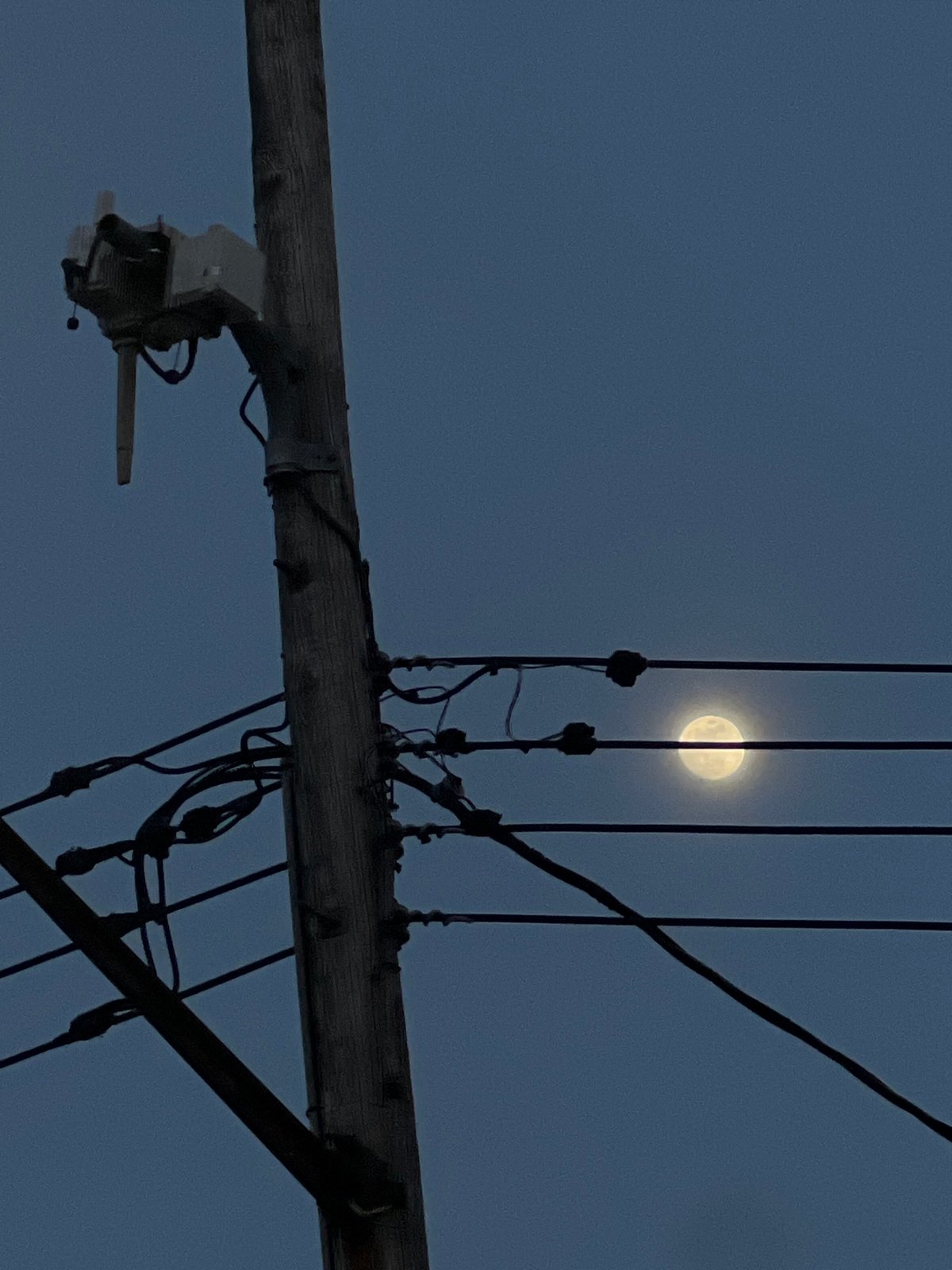Full moon rises behind utility pole in New York