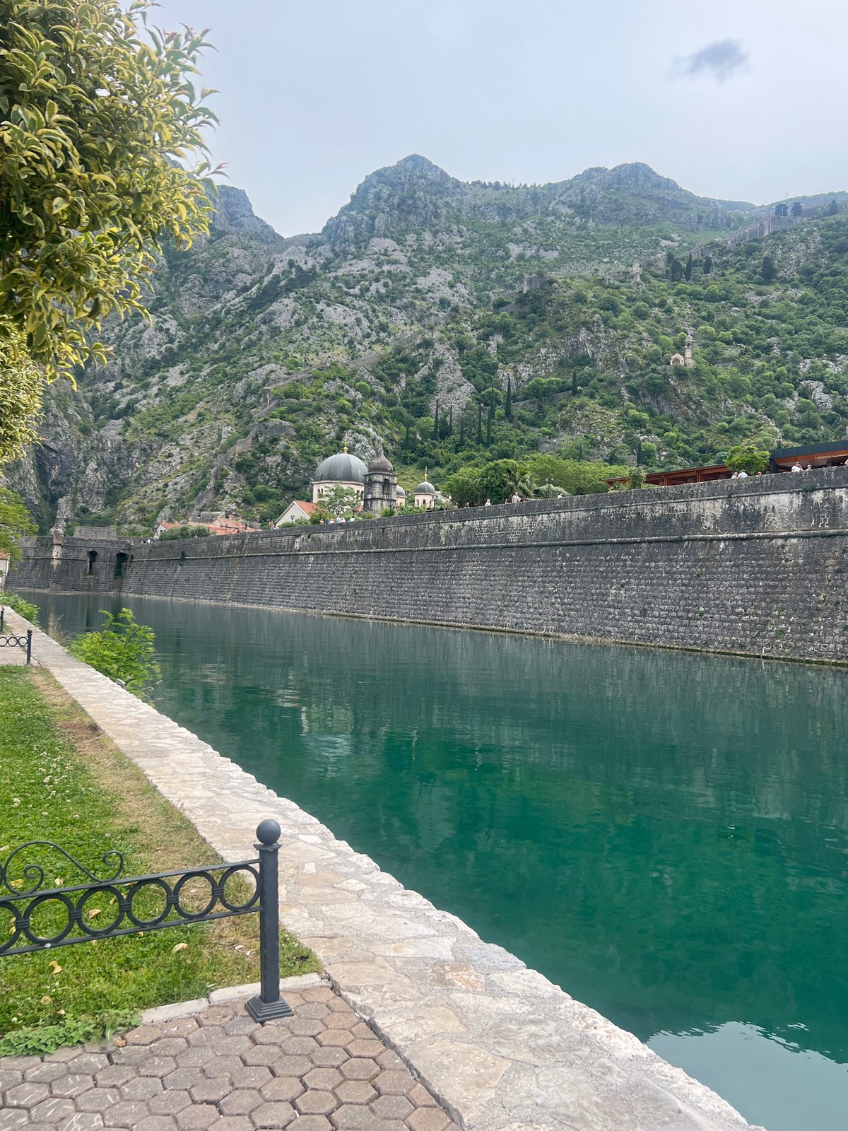Visitor documents historic Kotor waterfront and stone fortifications