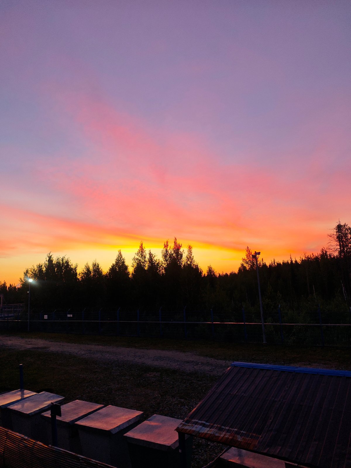Gas flare burns at dusk over an industrial facility