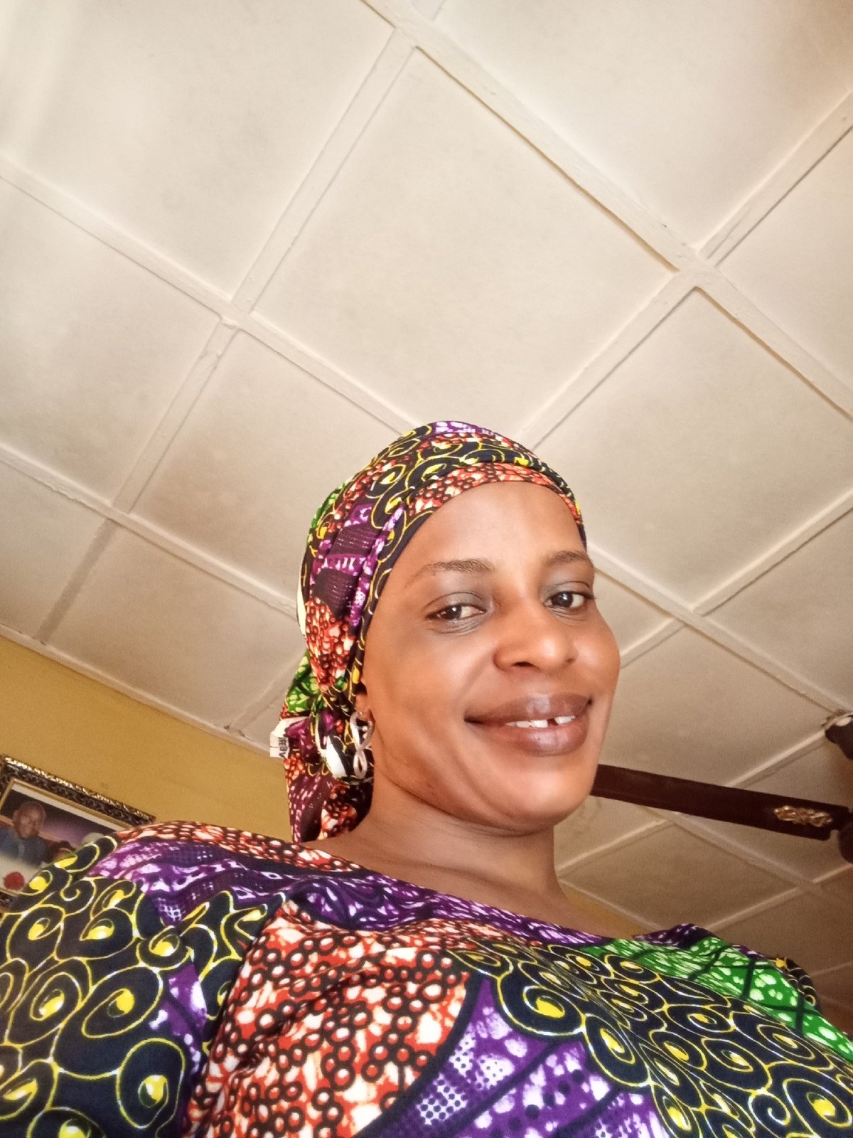 Woman in colorful headscarf photographed smiling indoors in Narayi