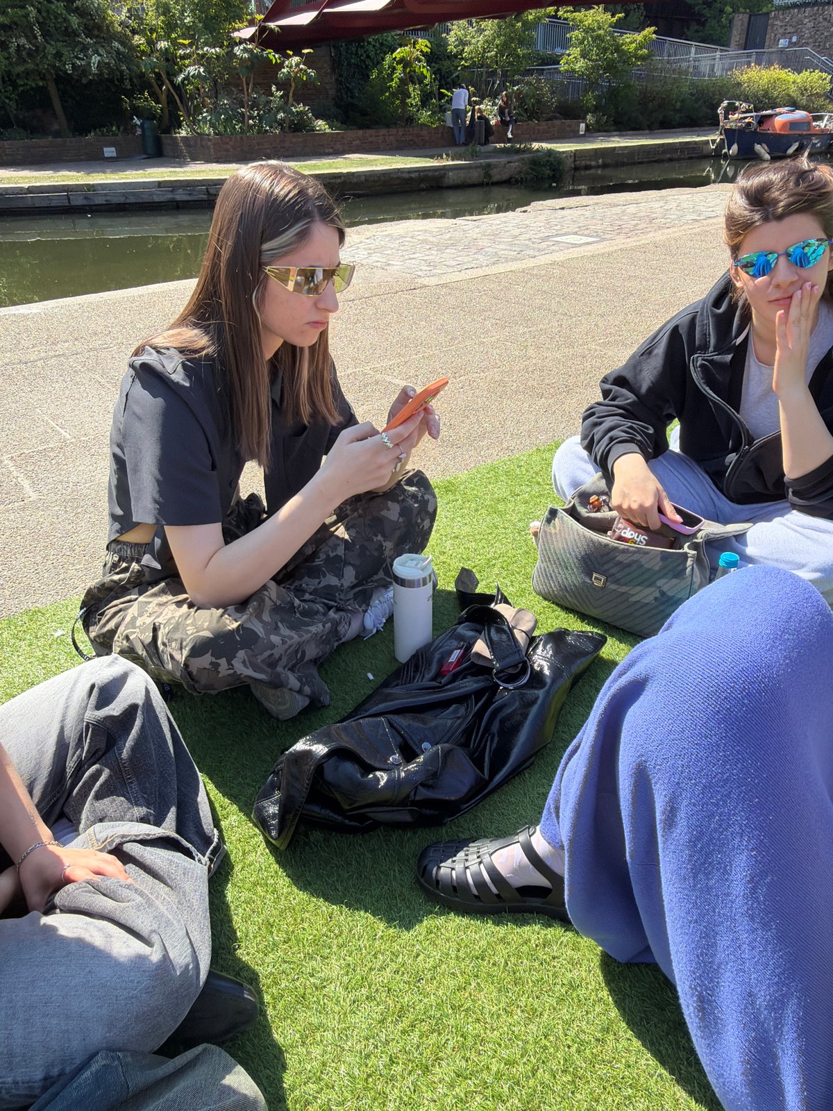 Four people gather on artificial grass by Regent's Canal