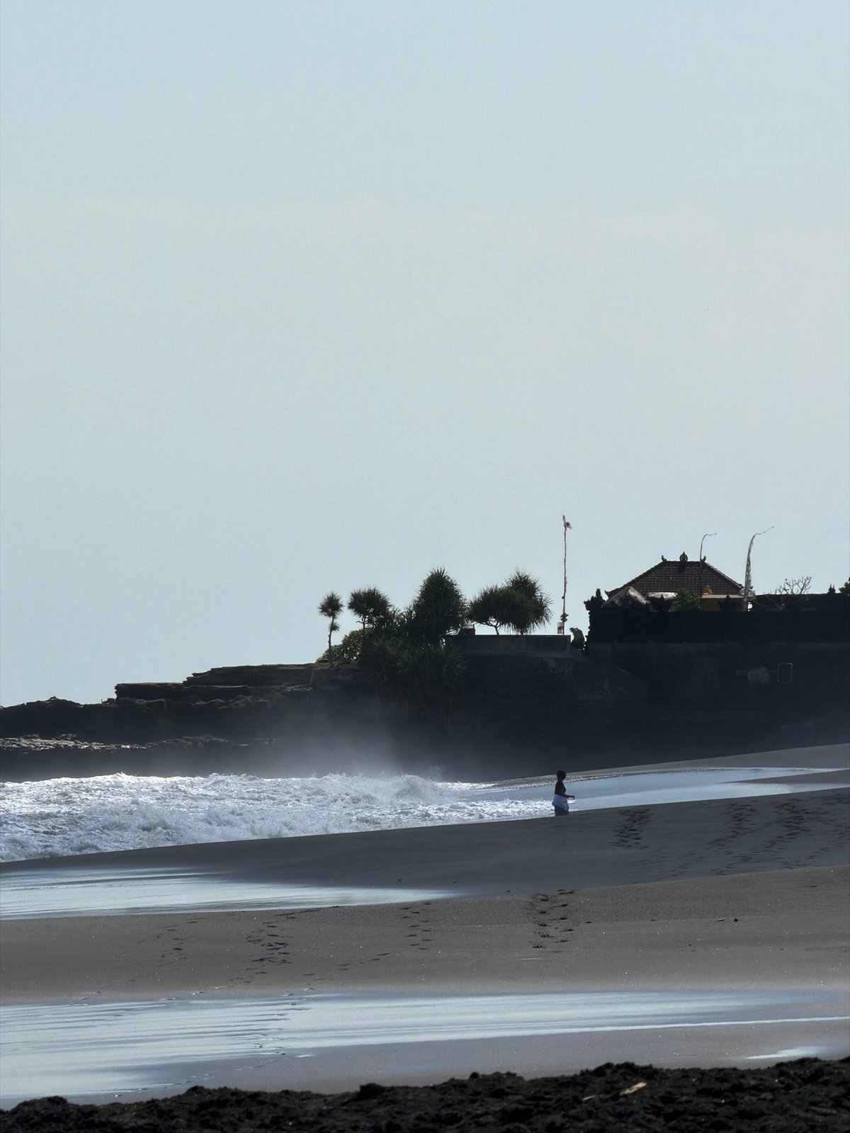 Volcanic beach and palm huts on a quiet Bali morning