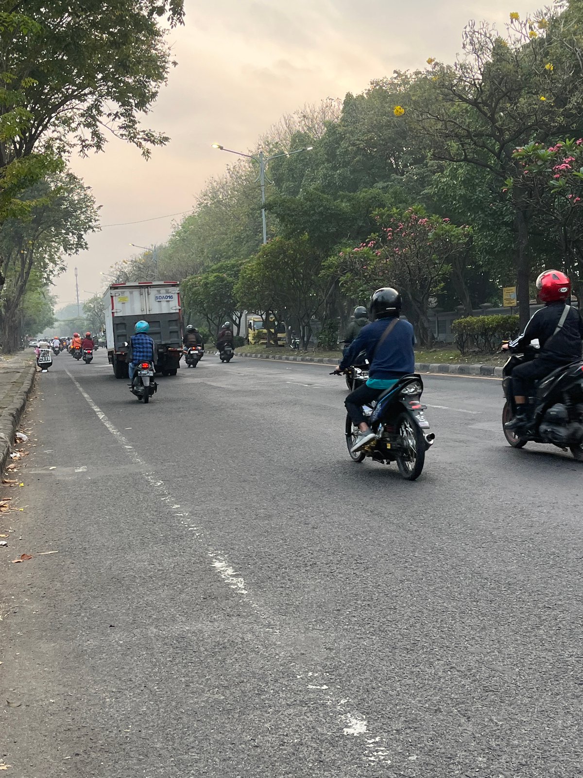 Motorcycle traffic flows through hazy streets of East Java