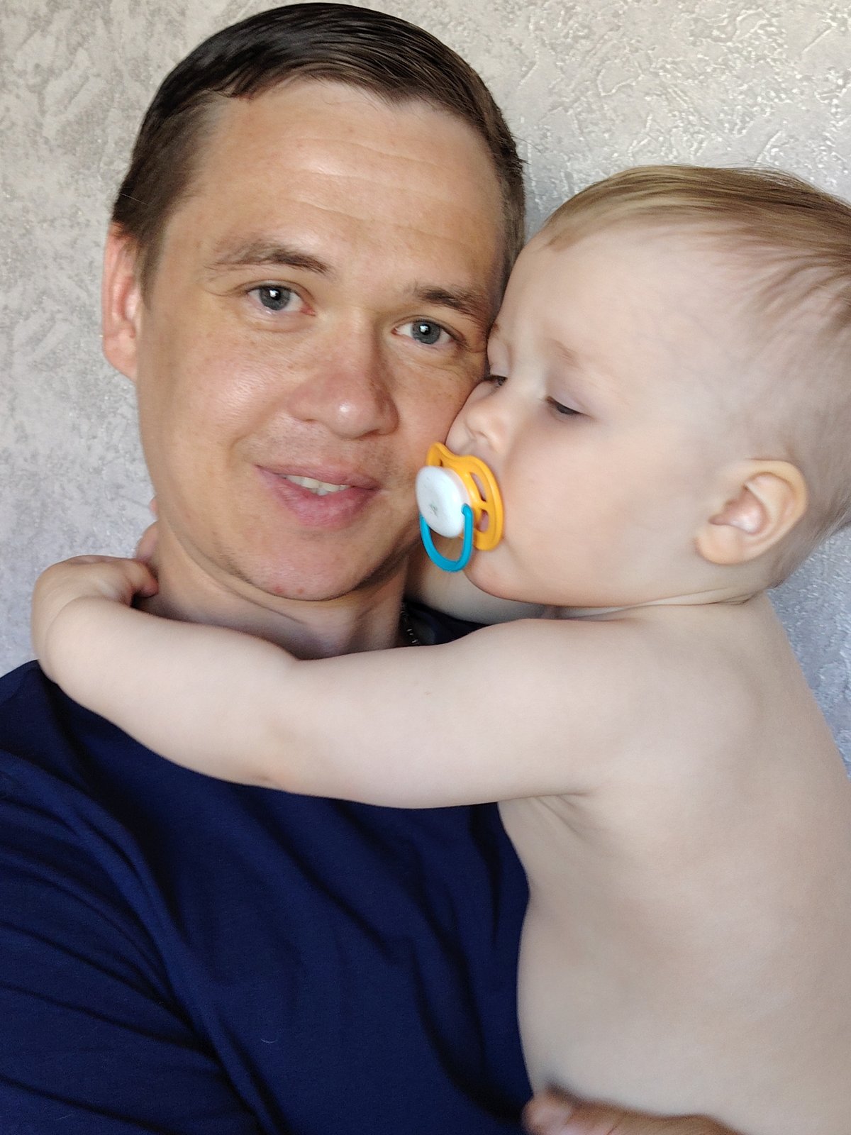Father holds baby in intimate morning moment, Chaikovsky Russia