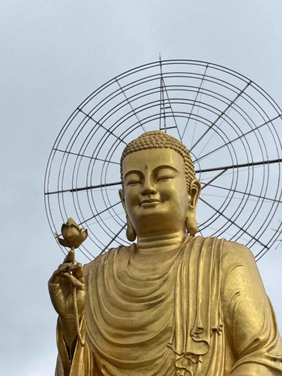Visitor documents golden Buddha statue and monk at Đà Lạt temple