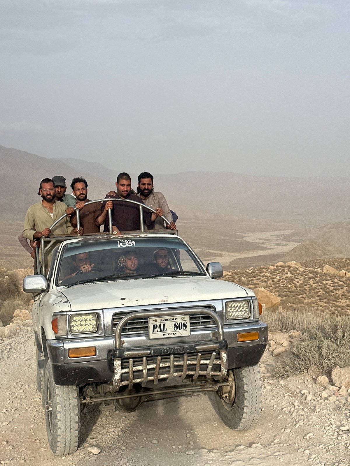 Group rides roll-cage Hilux through arid mountain terrain near Quetta