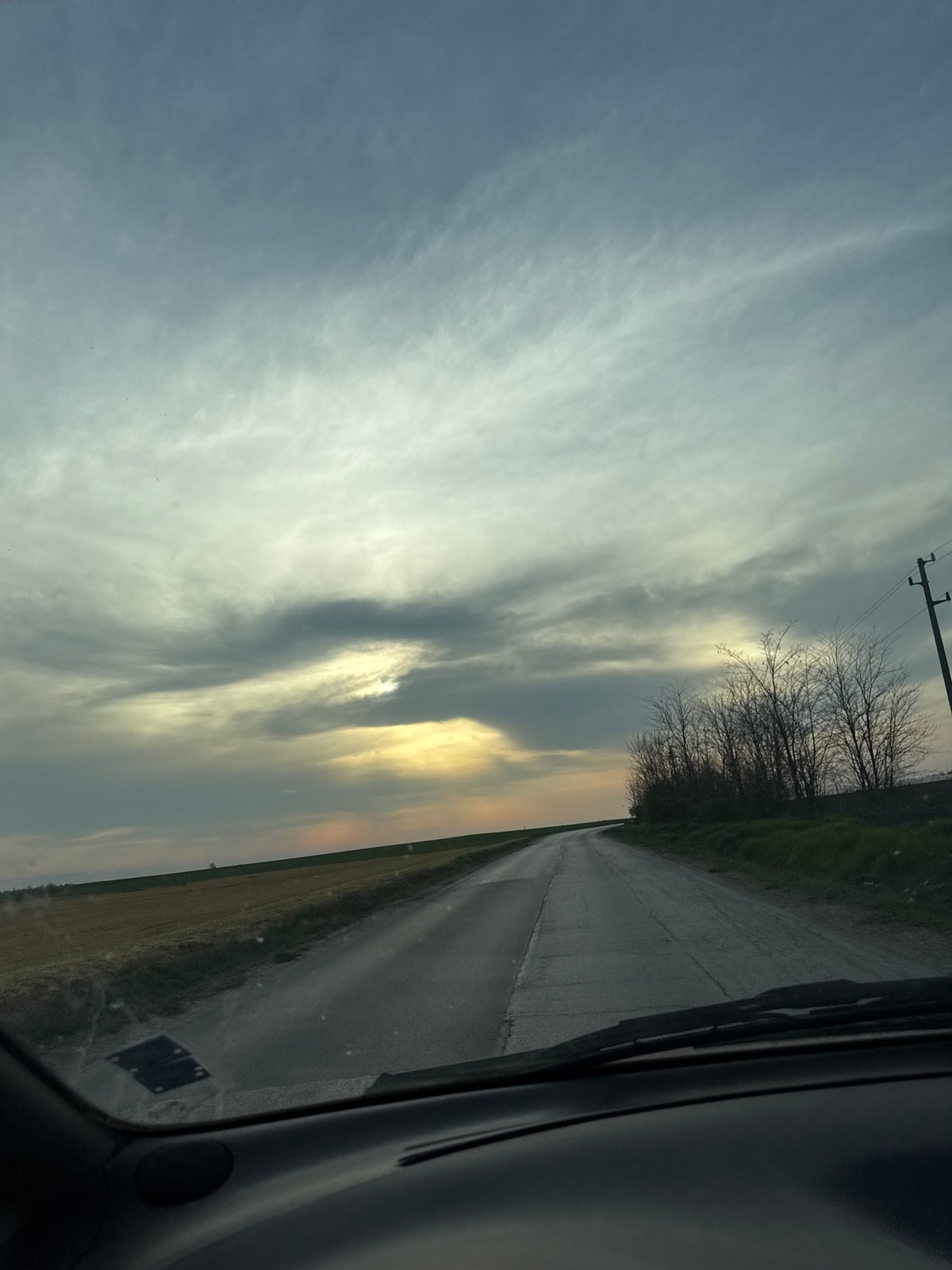 Motorist drives wet road through Bulgarian countryside fields