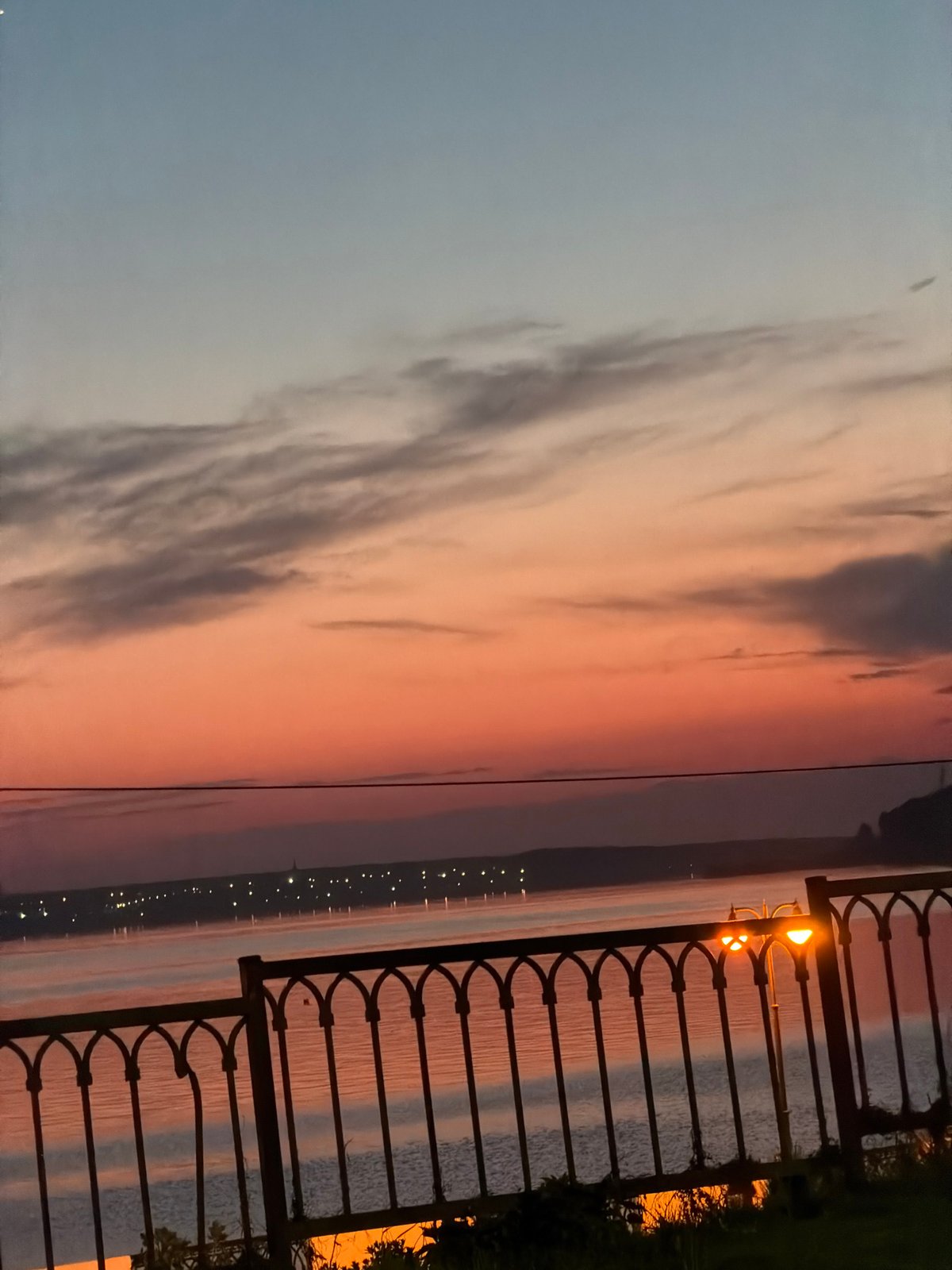 Sunset captured along Izhevsk waterfront with lampposts and fence