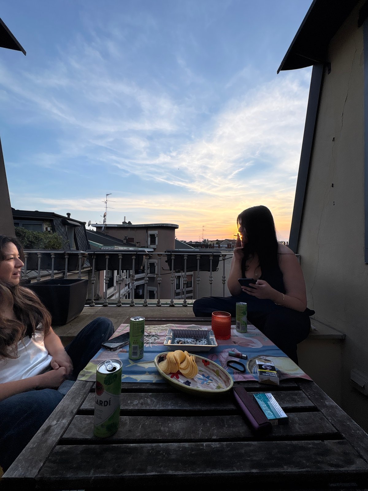 Two women enjoy sunset from Milan rooftop terrace