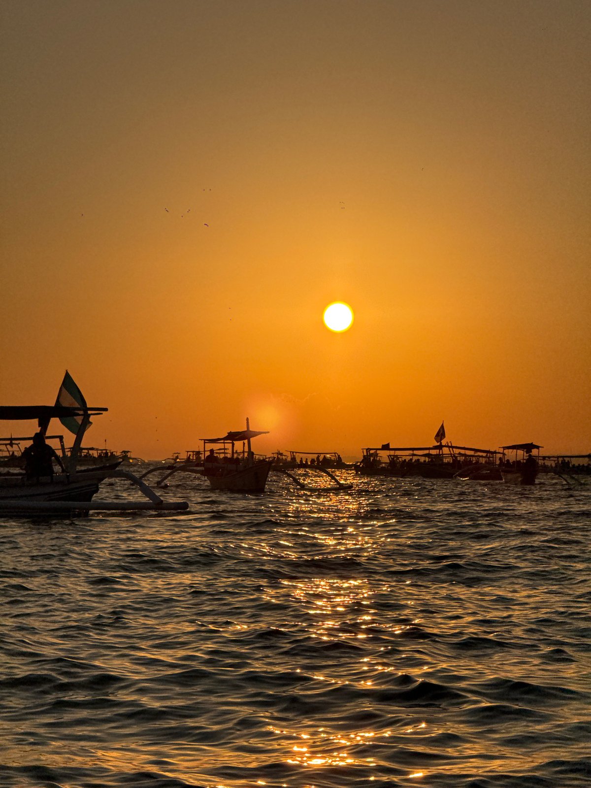 Traditional outrigger boats on the Bali Sea at sunset