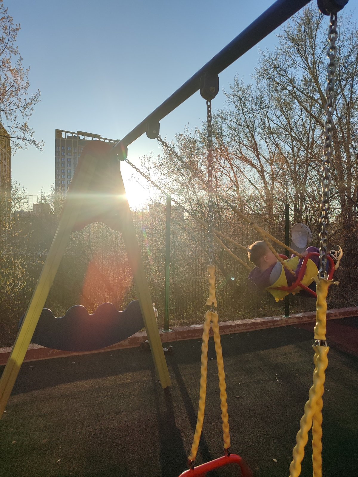 Children play at sunny Izhevsk playground during spring afternoon