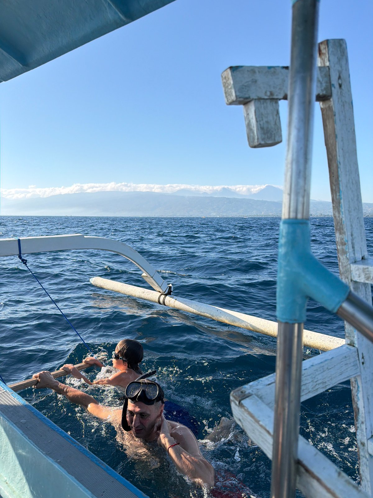 Swimming and drifting near an outrigger boat off the Indonesian coast