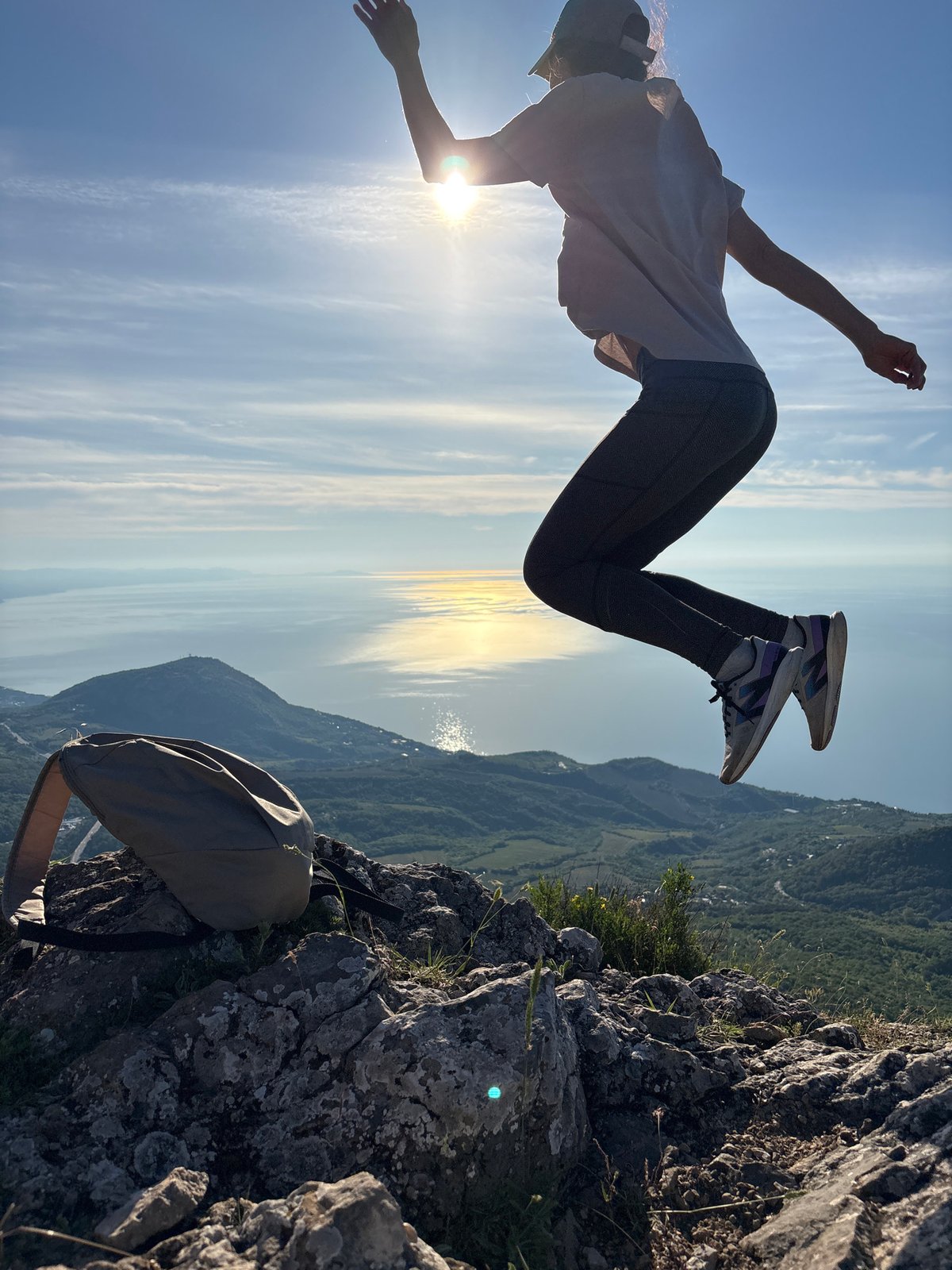 Person captured jumping on mountain peak overlooking coast