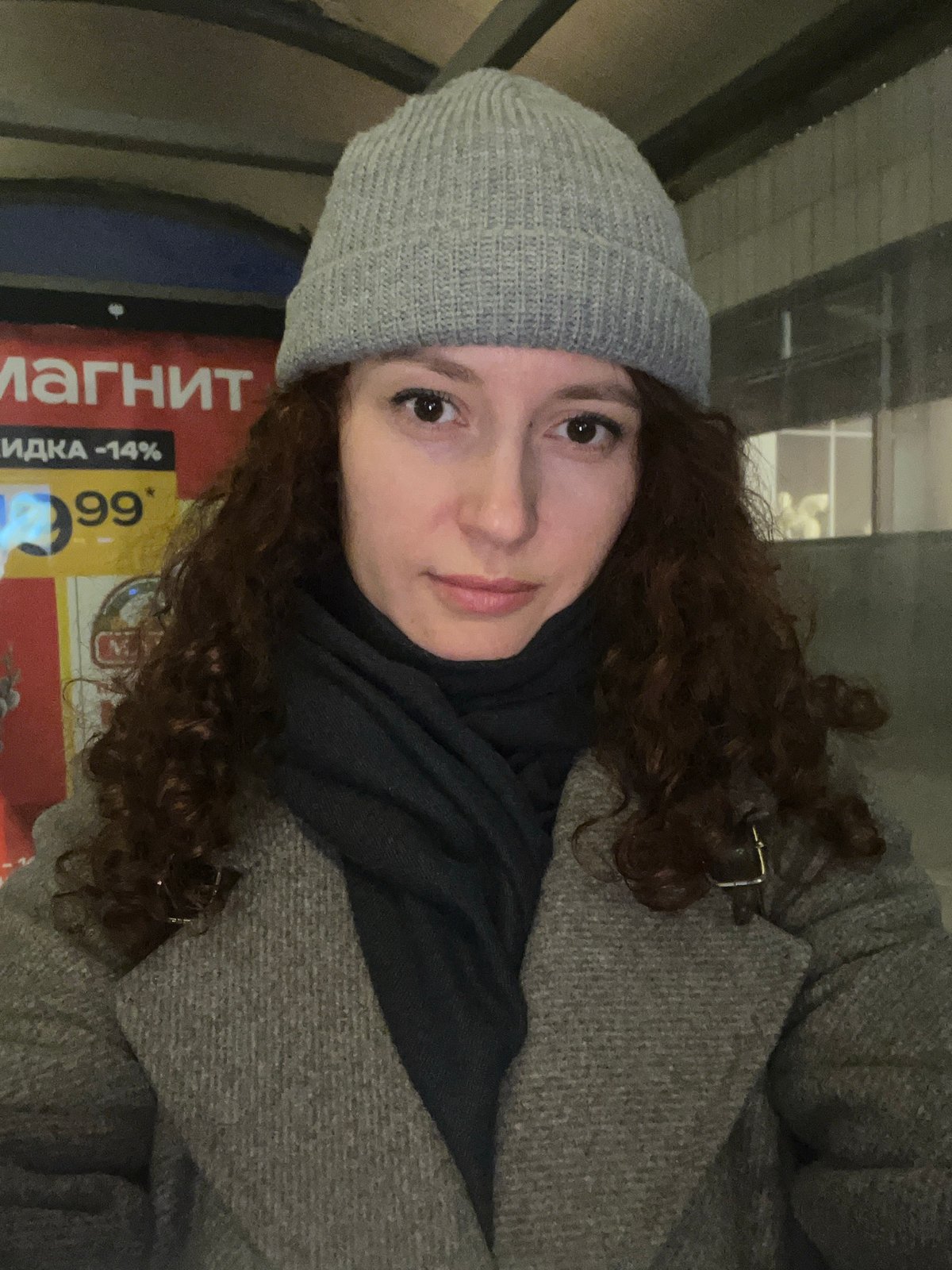 Woman takes selfie near store in rainy Saint Petersburg