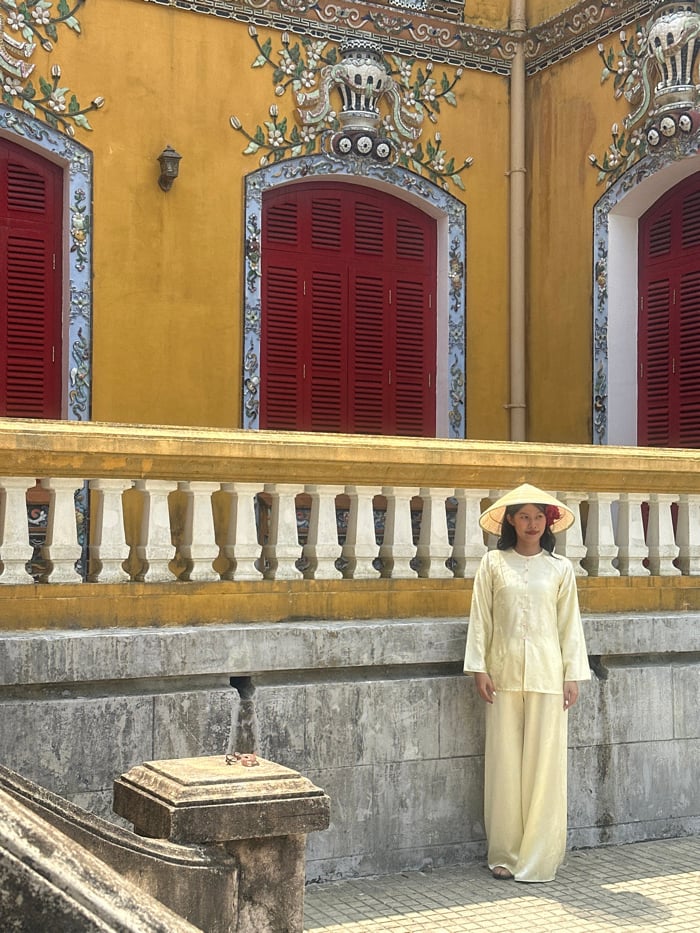Woman stands before yellow structure in Hue Imperial City