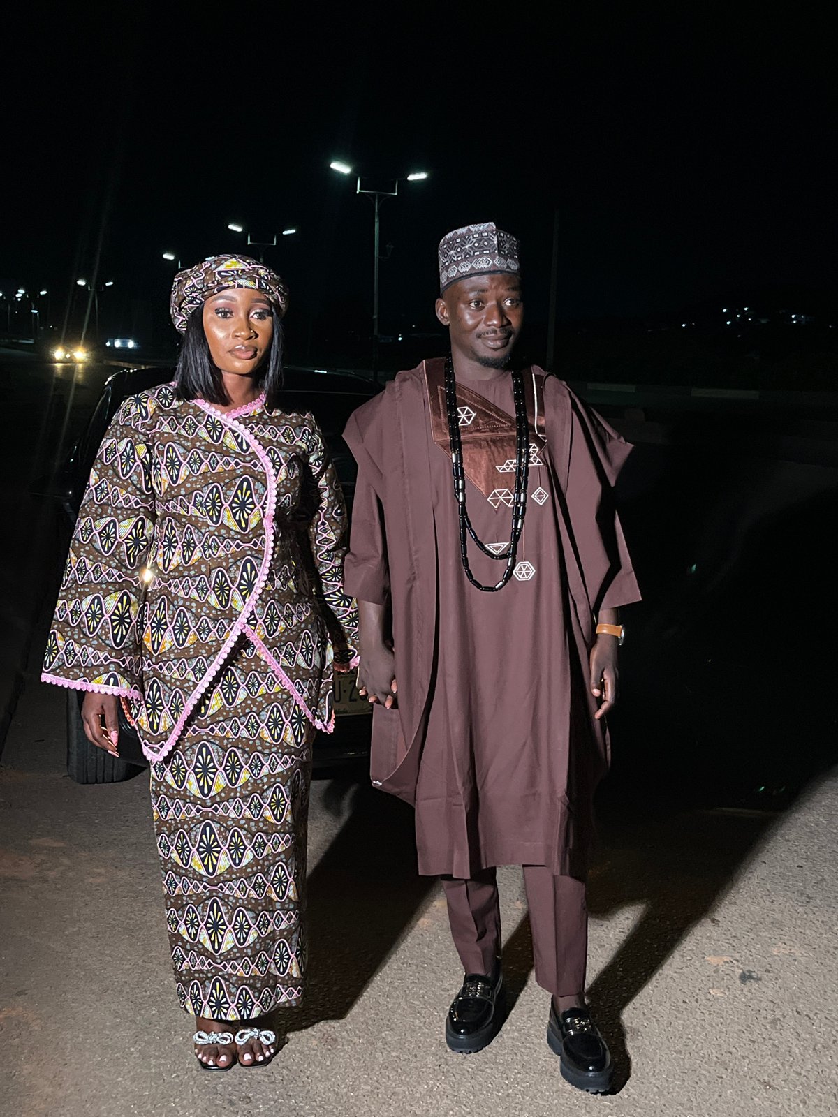 Couple in matching traditional outfits poses at night in Gura Top