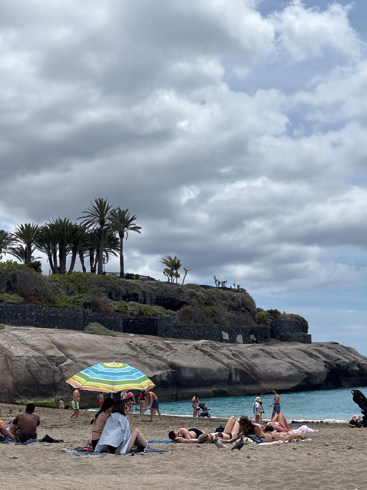 Cloudy day beach activity continues in Adeje, Spain